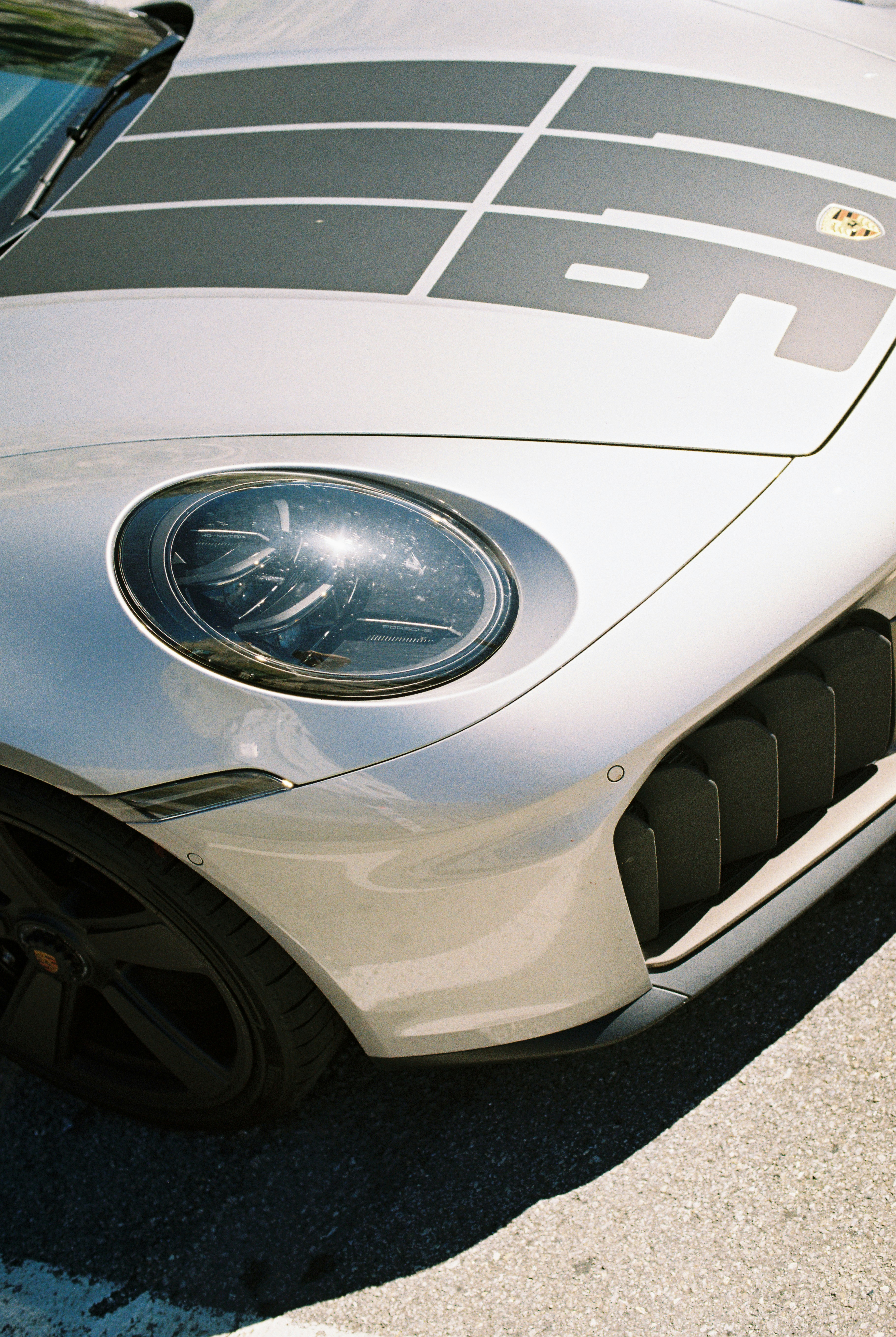 Close-up of a silver Porsche sports car hood with black racing stripes