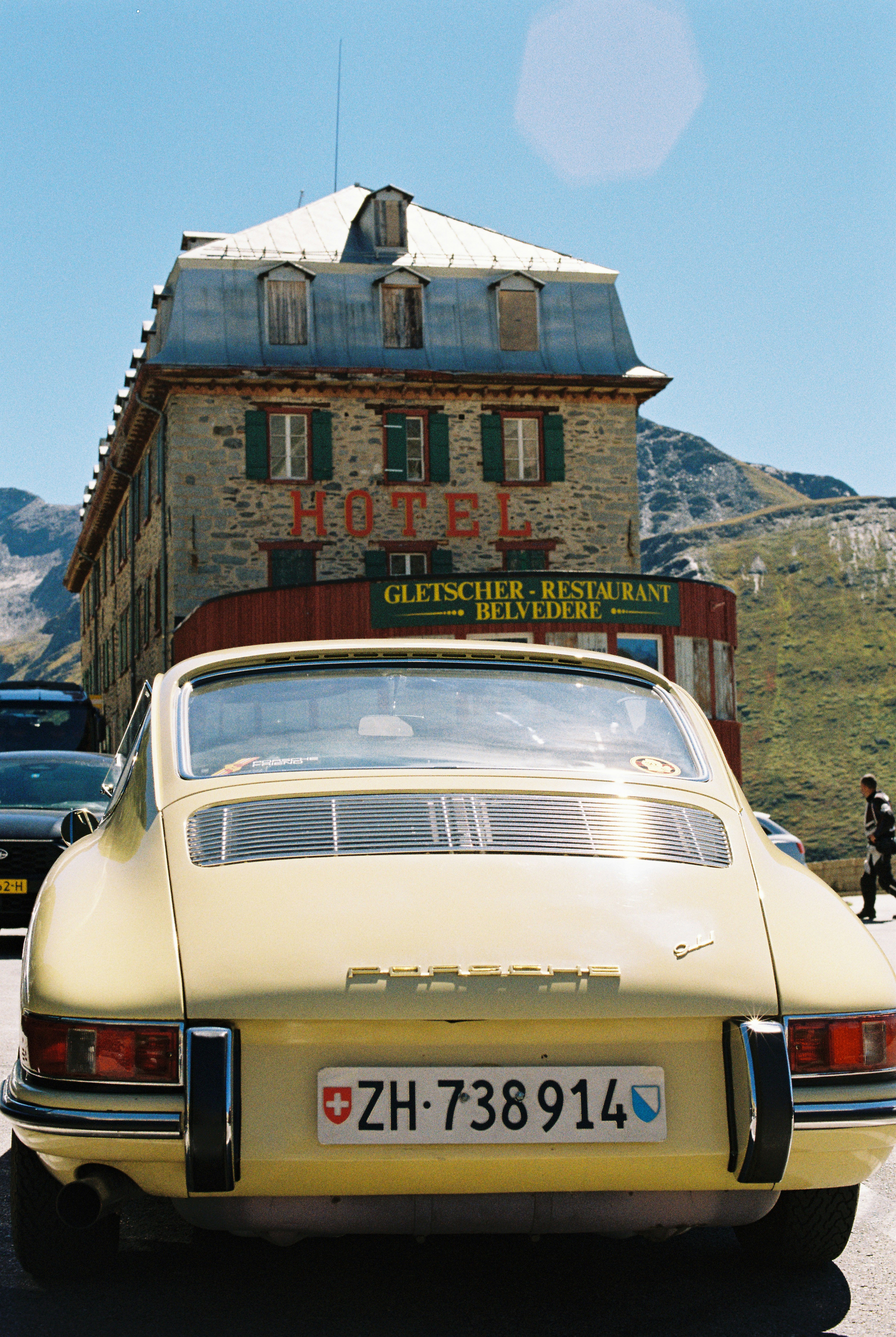 A vintage yellow Porsche parked before the Hotel Belvedere in the Swiss Alps