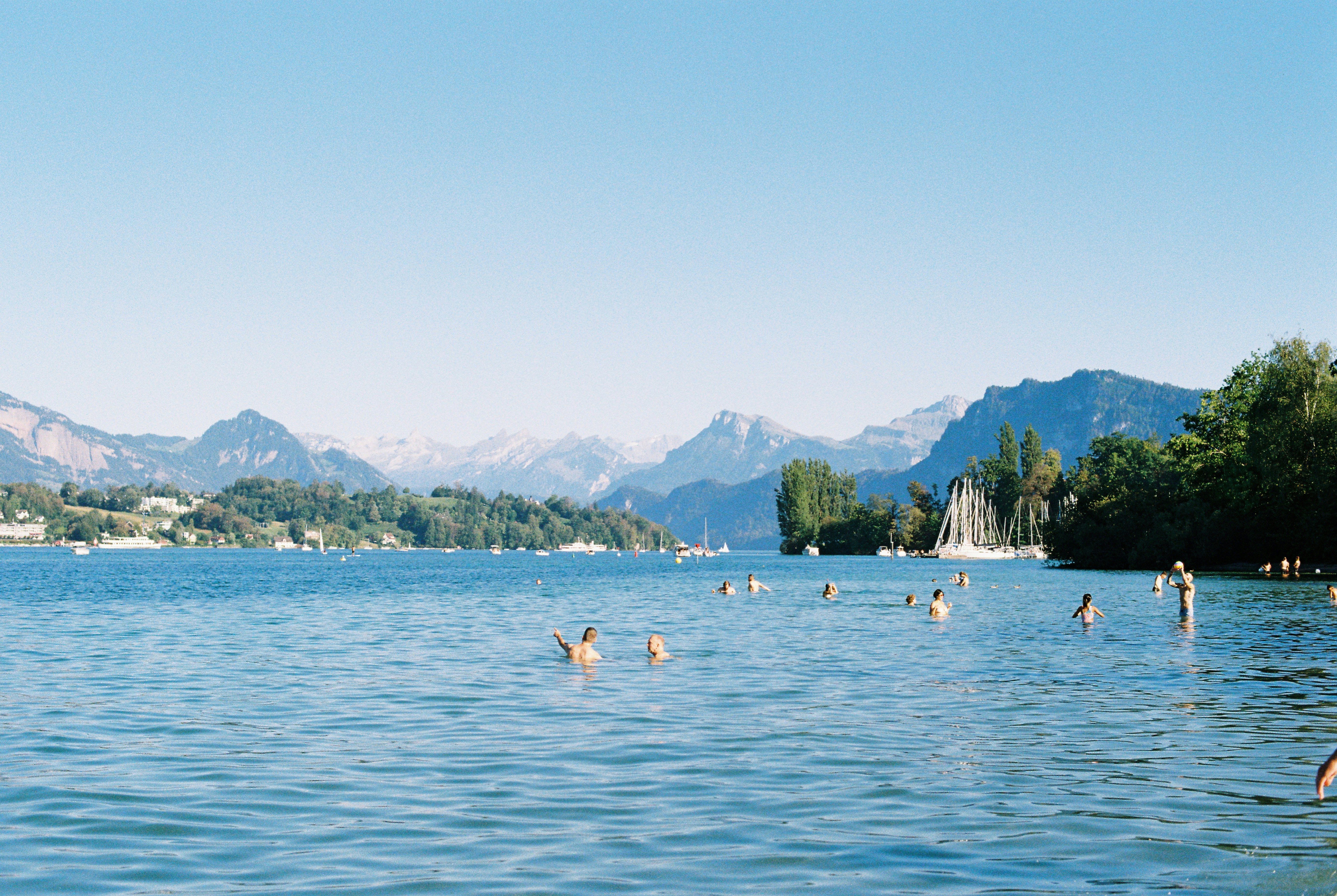 People swimming in a blue lake with mountains in the background