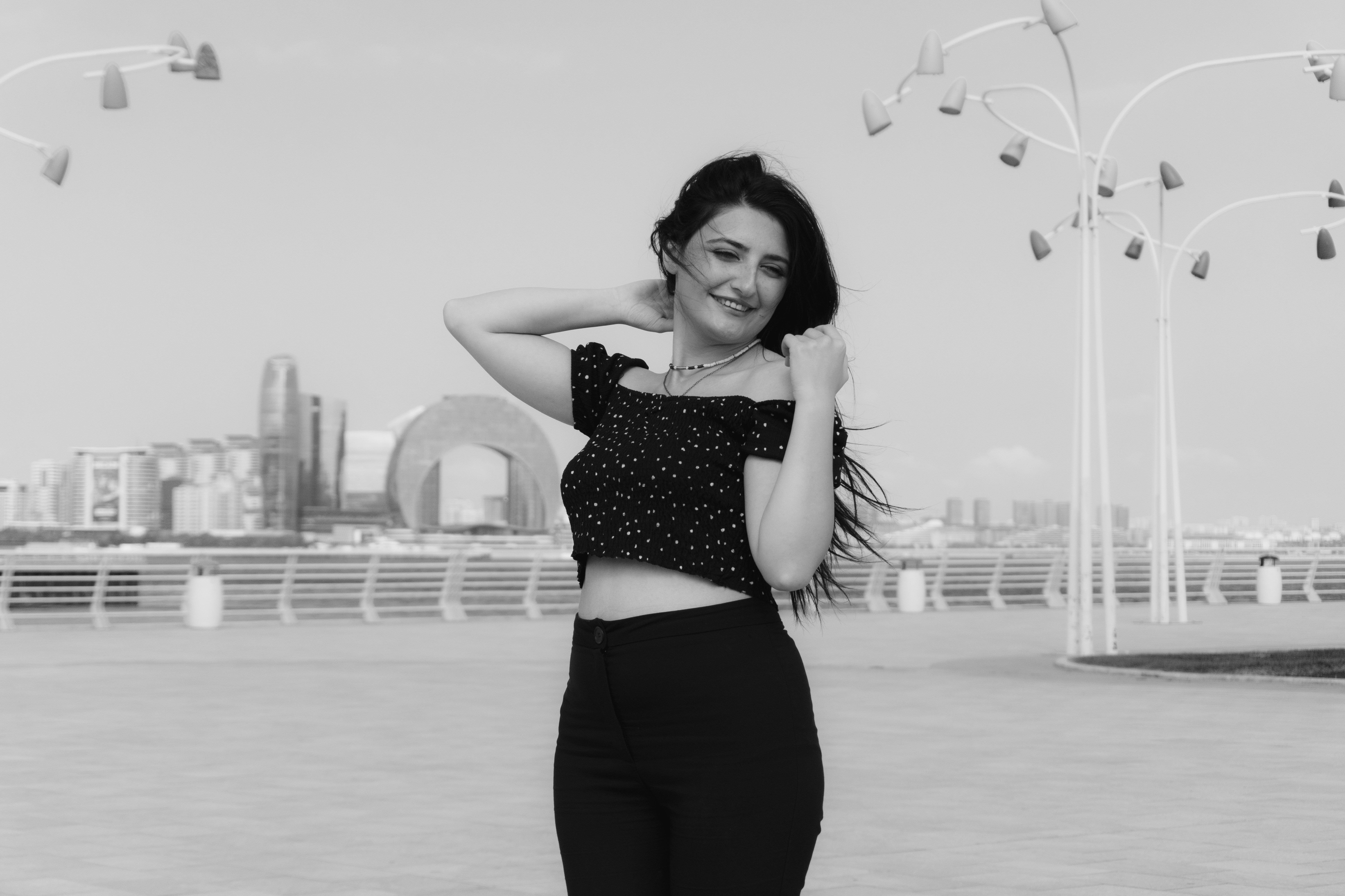 A woman in a polka dot crop top on a waterfront promenade