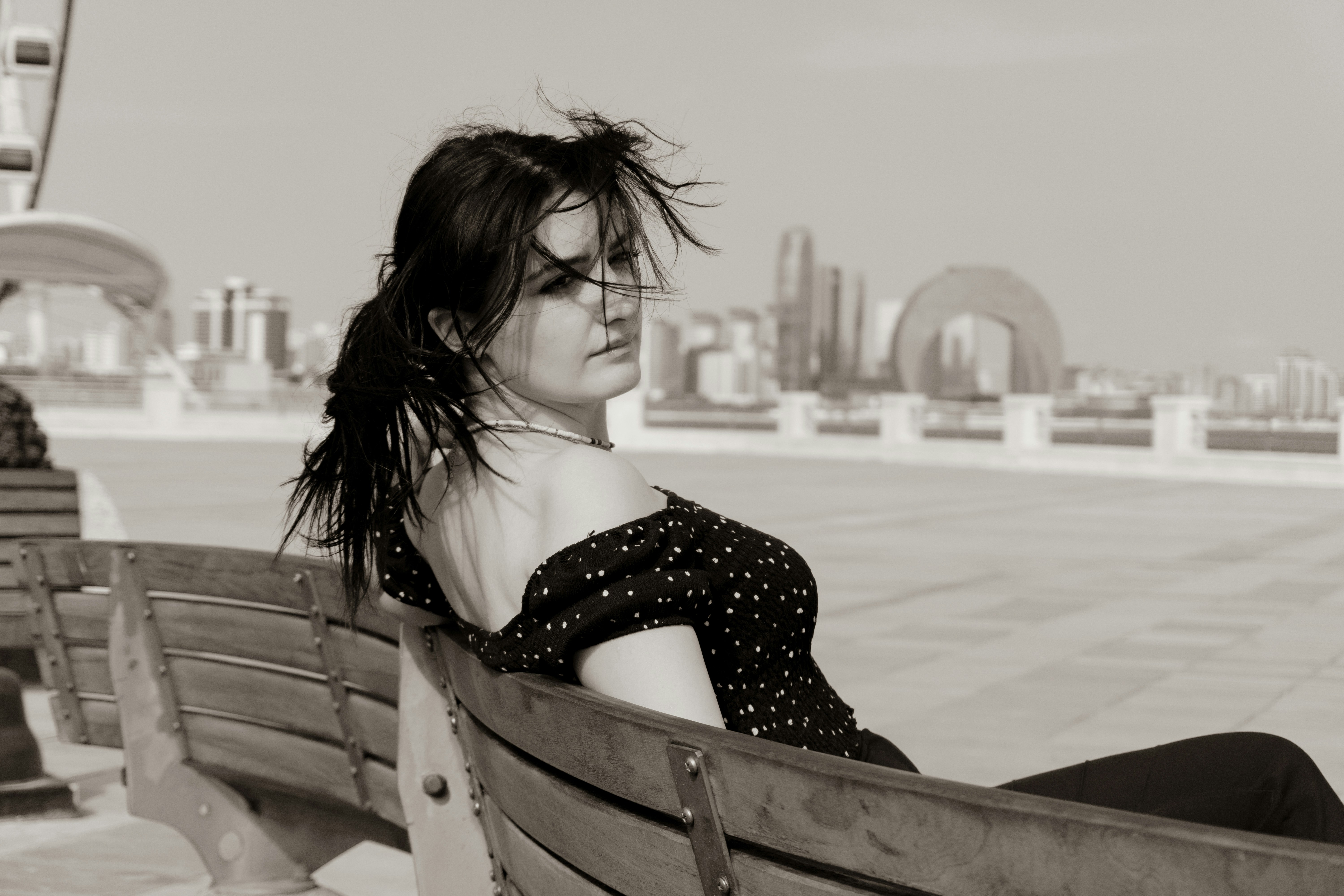 A woman in a polka dot top on a wooden bench in Abu Dhabi
