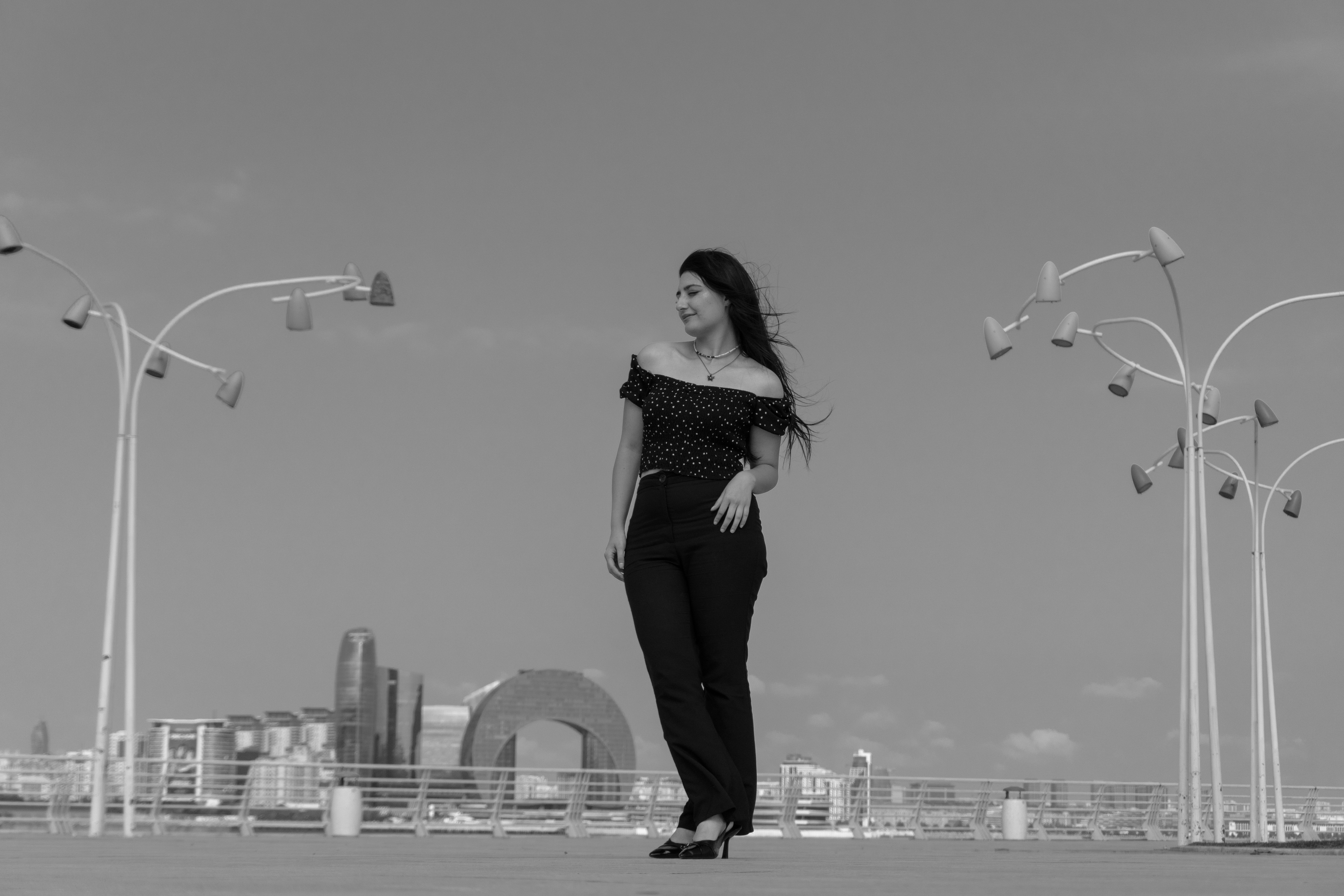 A woman in a polka dot off-shoulder top on a city promenade