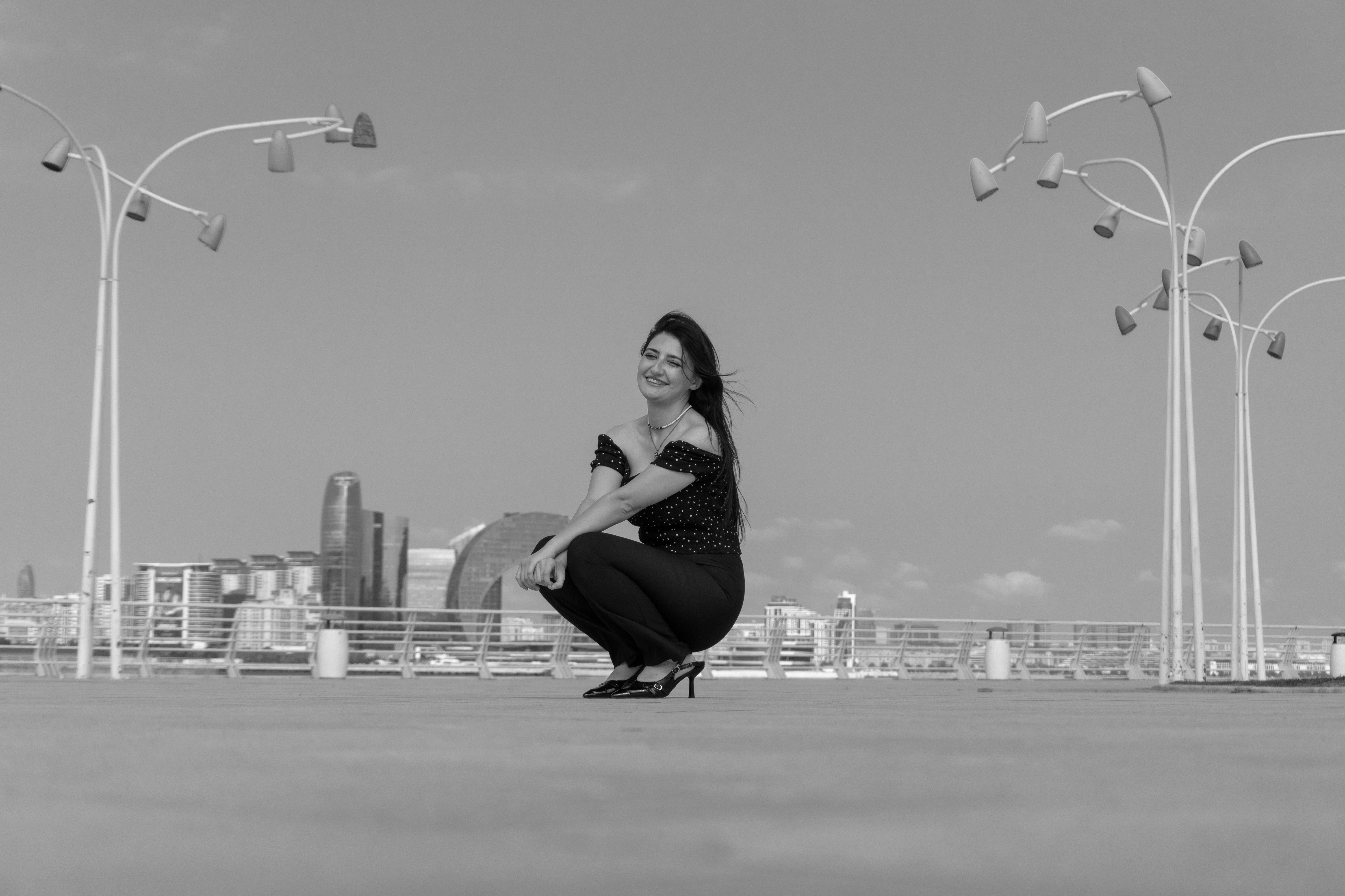 A woman in a polka dot top crouching on a city promenade