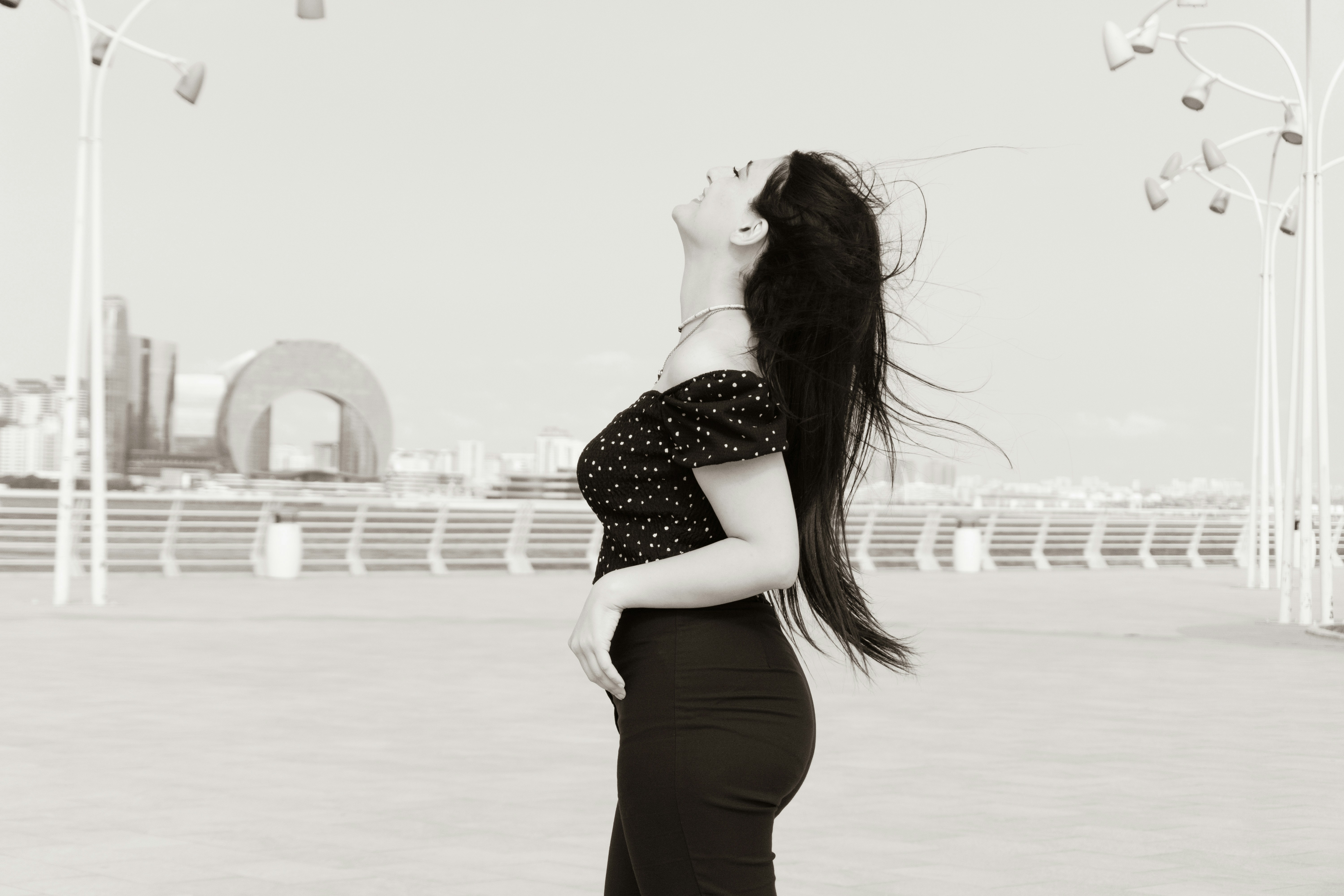 A woman in a polka dot top with hair blowing in the wind