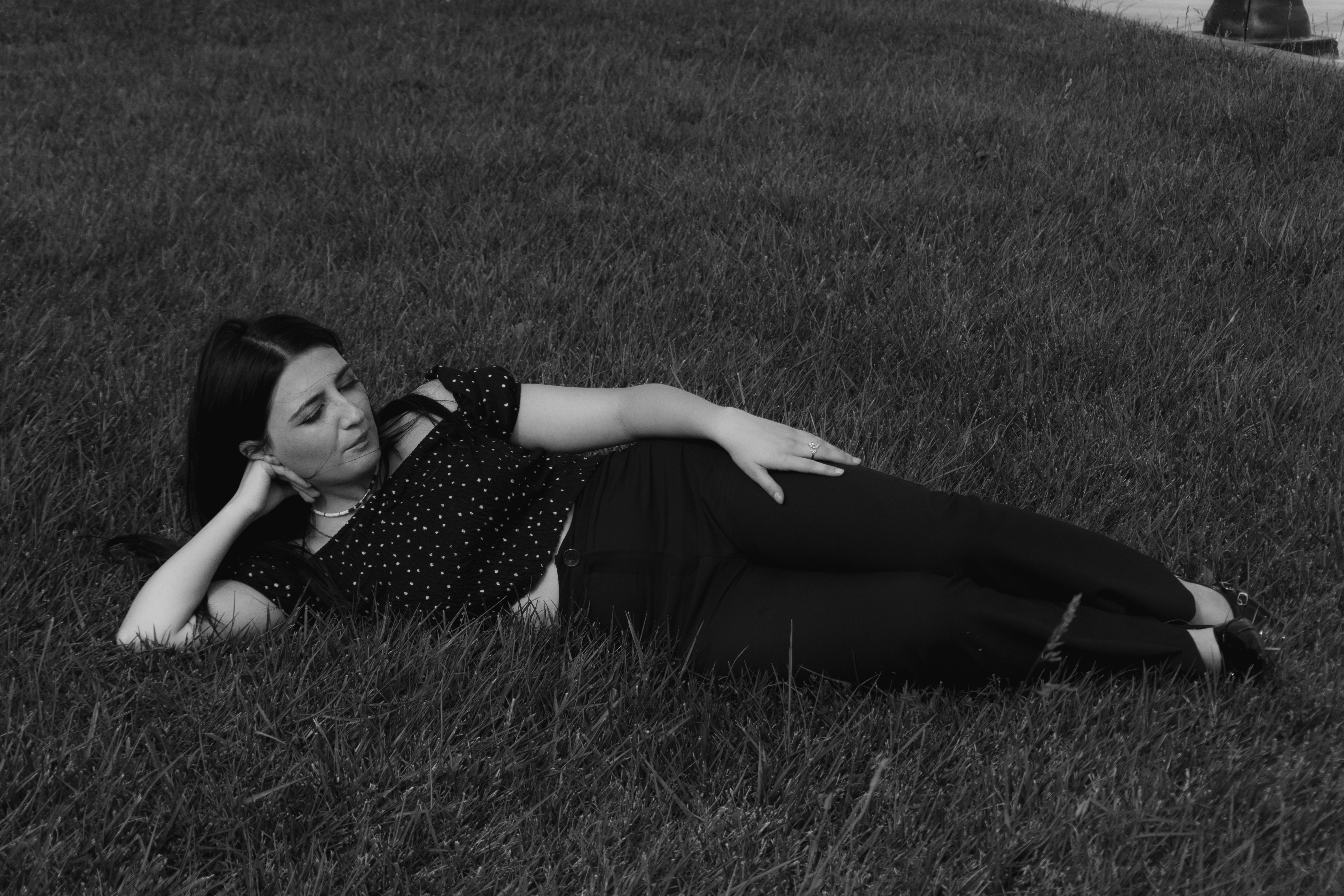 A woman in a polka dot top lying on green grass