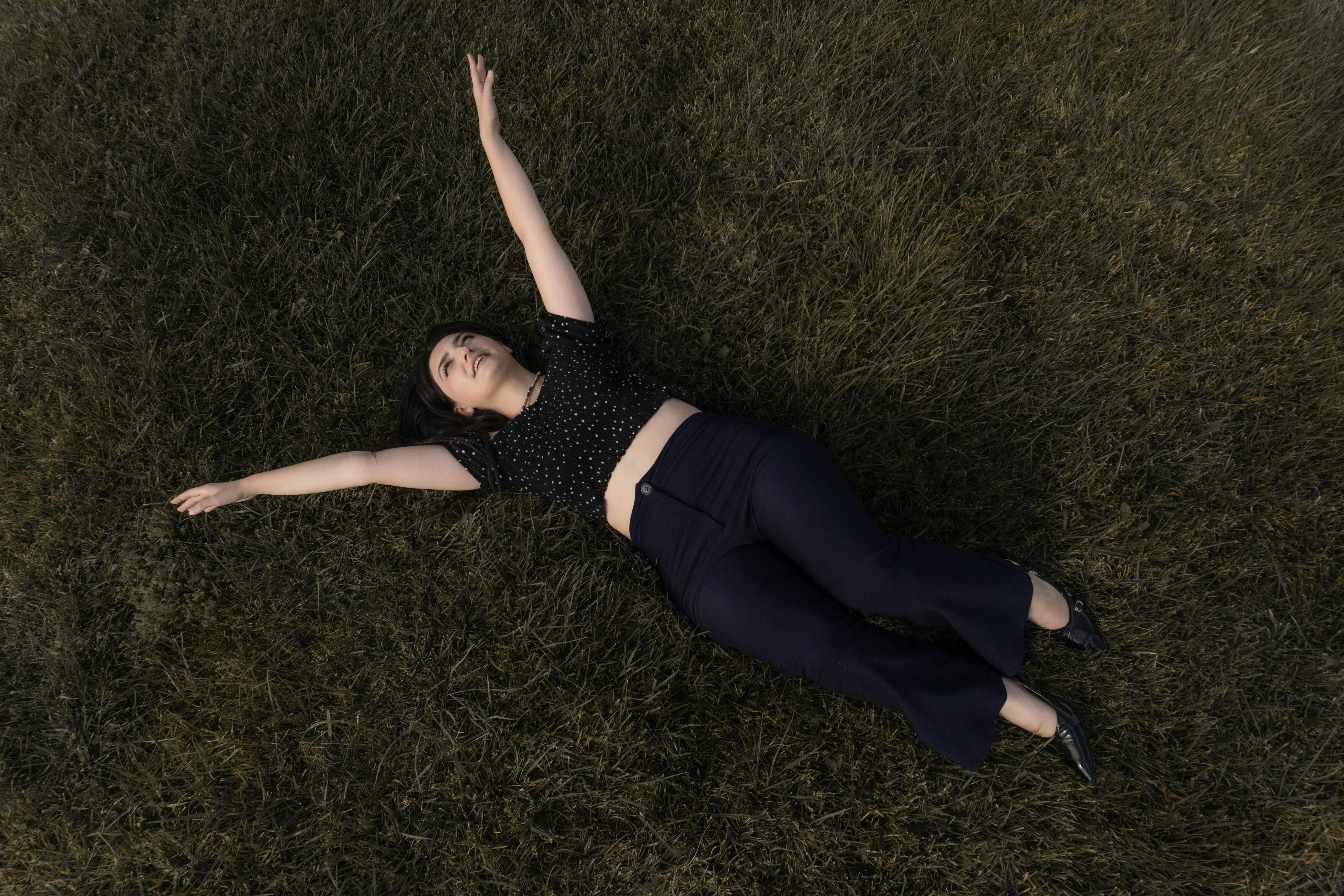 A woman in a black polka dot top lying on green grass
