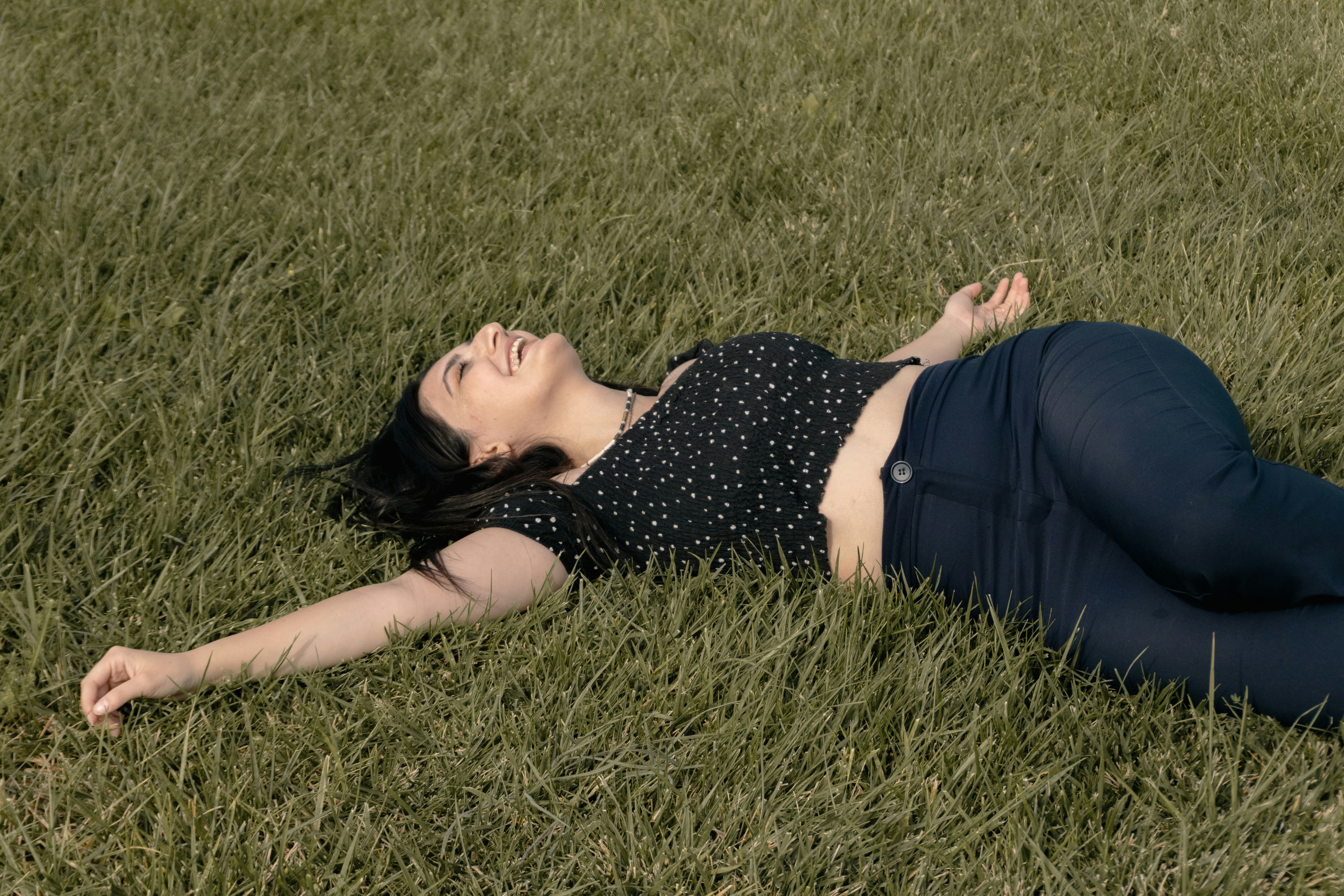 A woman in a black polka dot top lying on green grass
