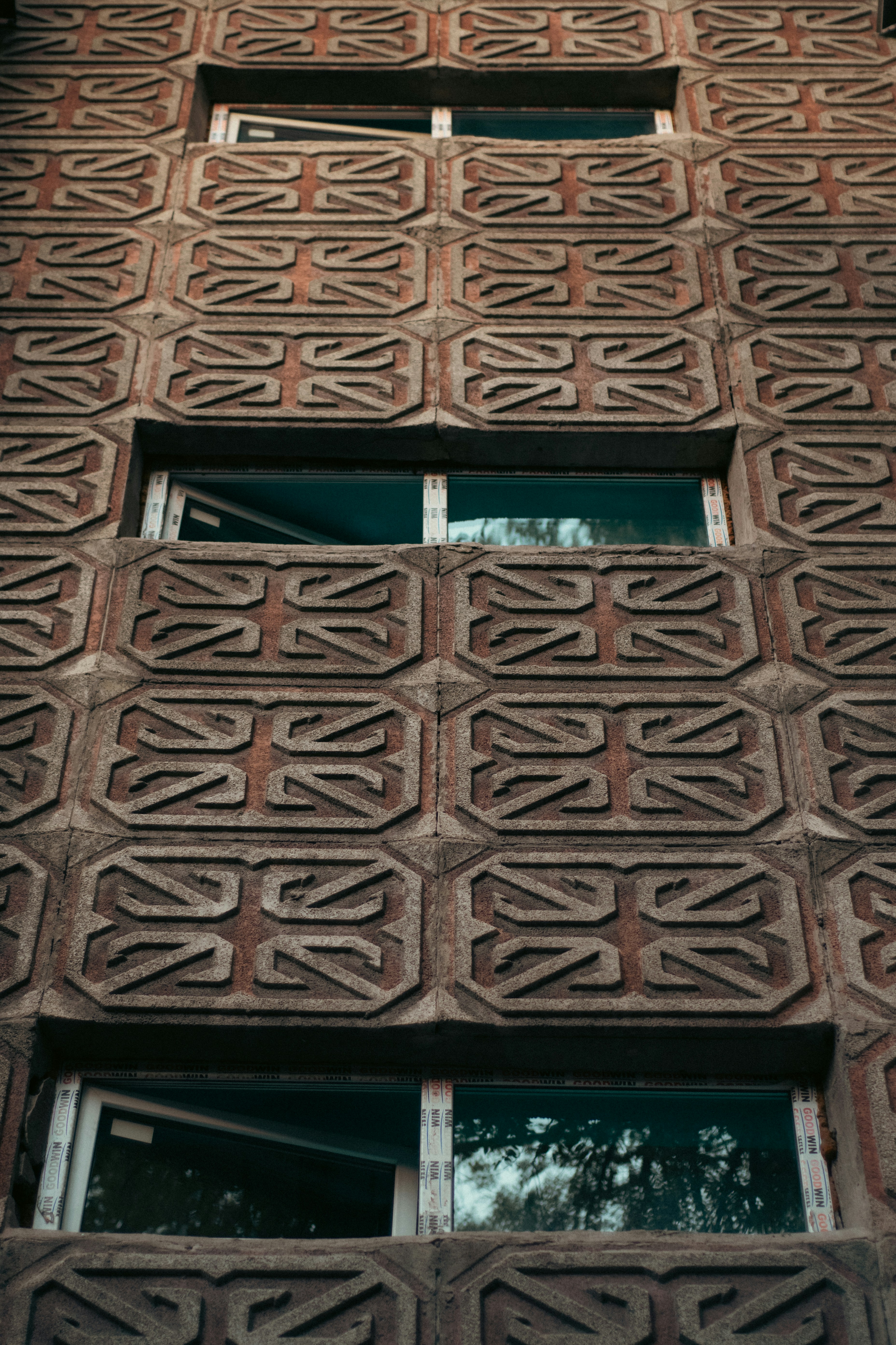 Une façade en béton avec des motifs géométriques répétés et des fenêtres rectangulaires