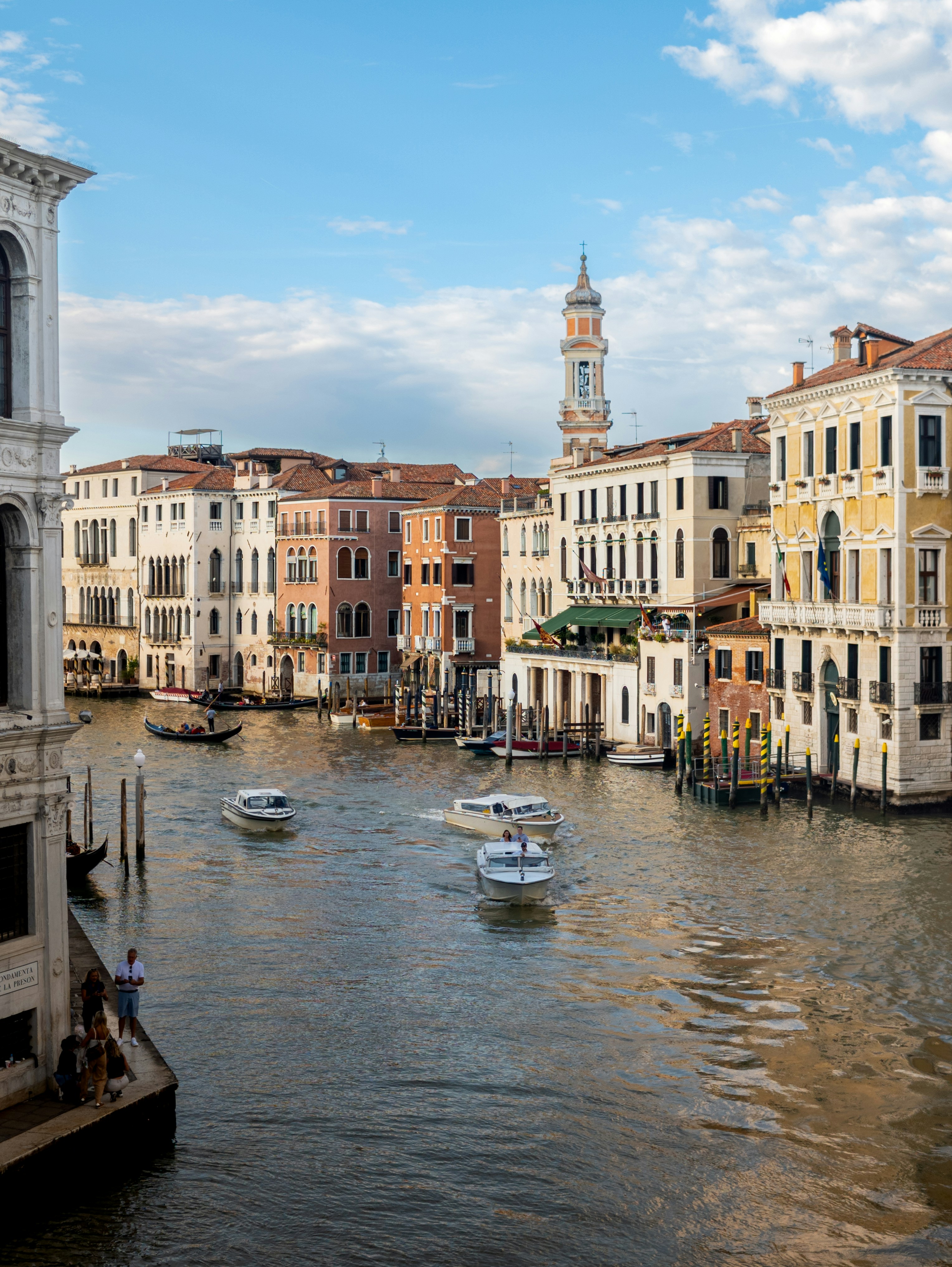Boats on the Grand Canal in Venice with historic buildings and a bell tower