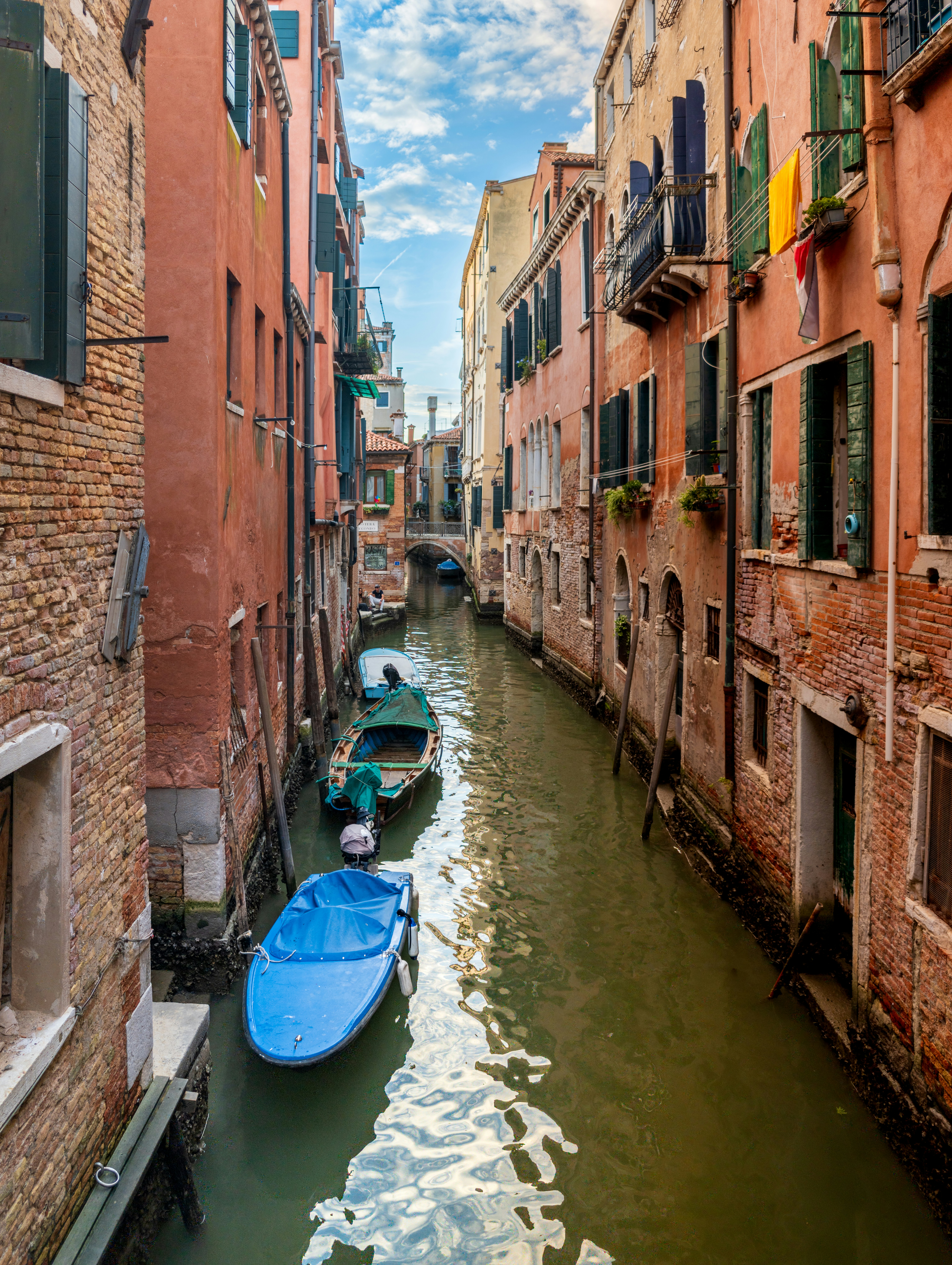 Barcos atracados en un canal estrecho entre altos edificios de ladrillo en Venecia, Italia