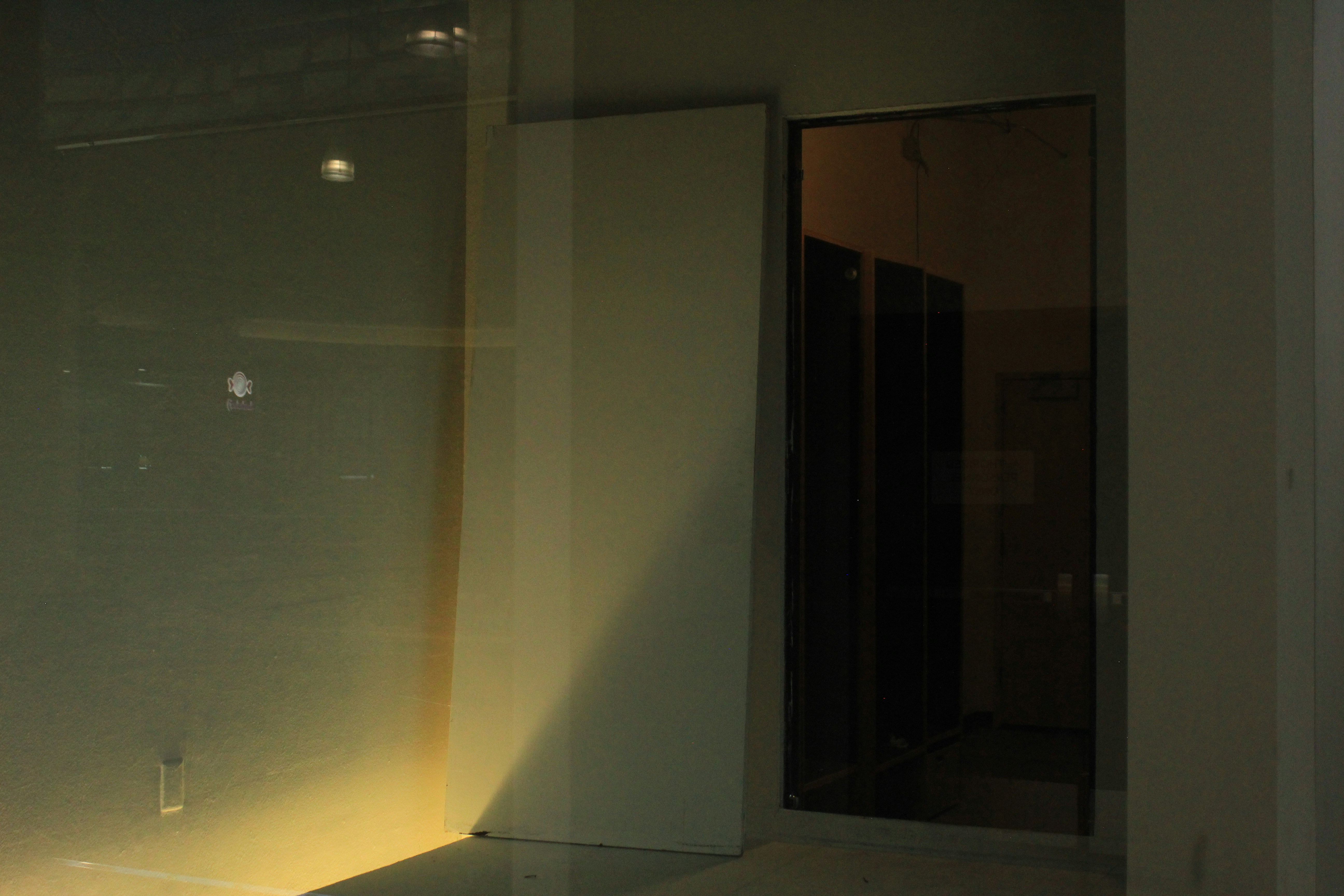 A dark doorway beside a wall illuminated by a warm yellow light