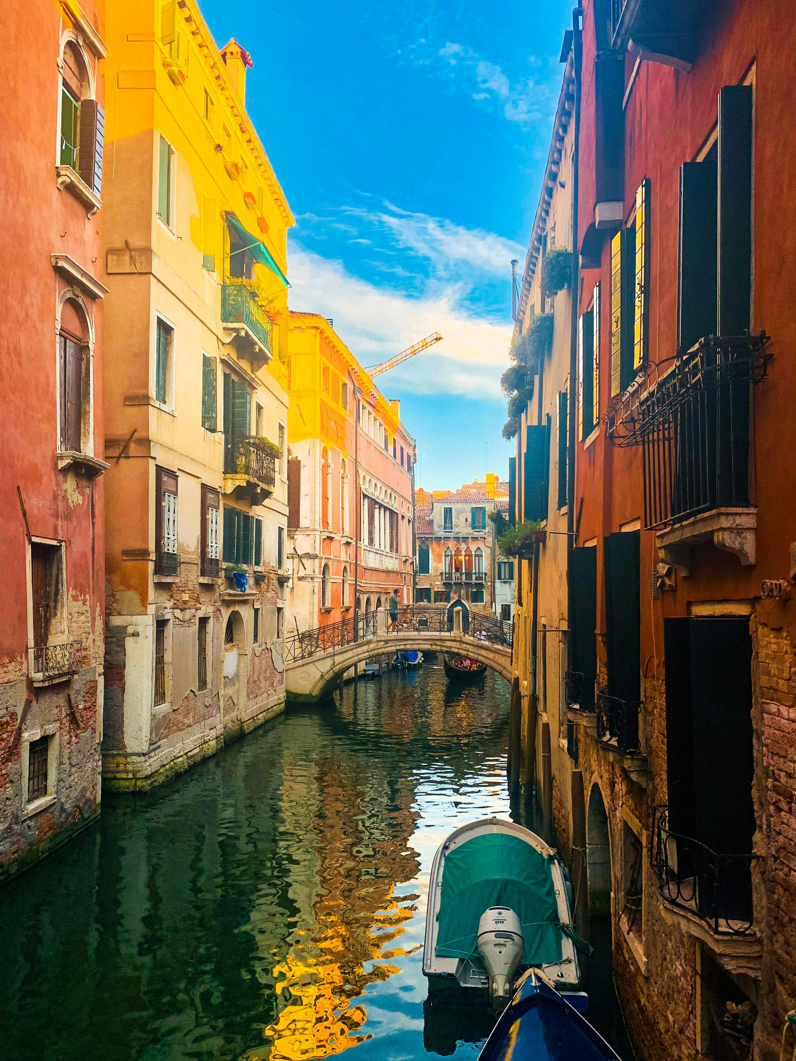 A narrow canal between colorful historic buildings in Venice with a small arched bridge