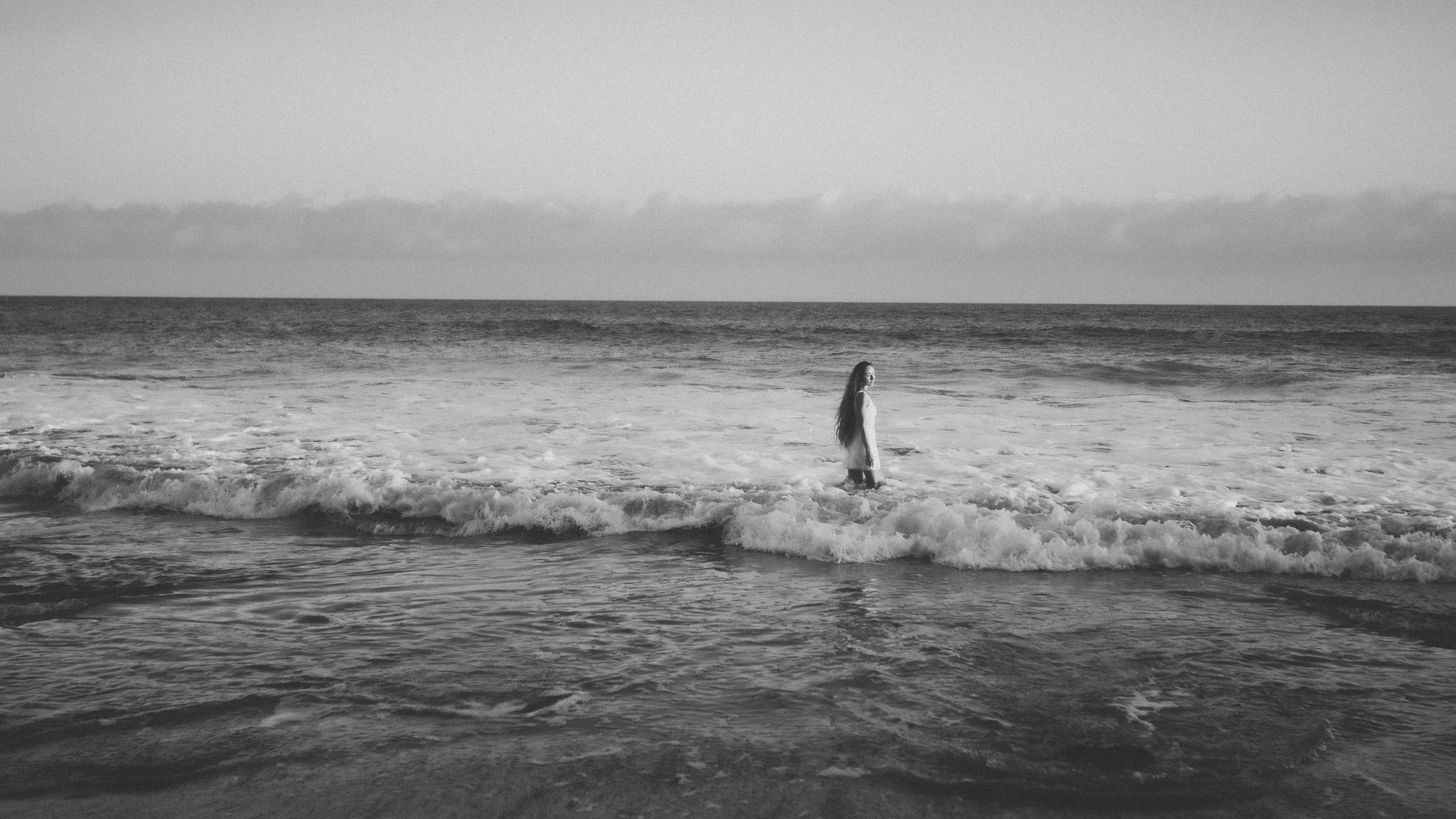A woman with long hair in the ocean surf at the shoreline