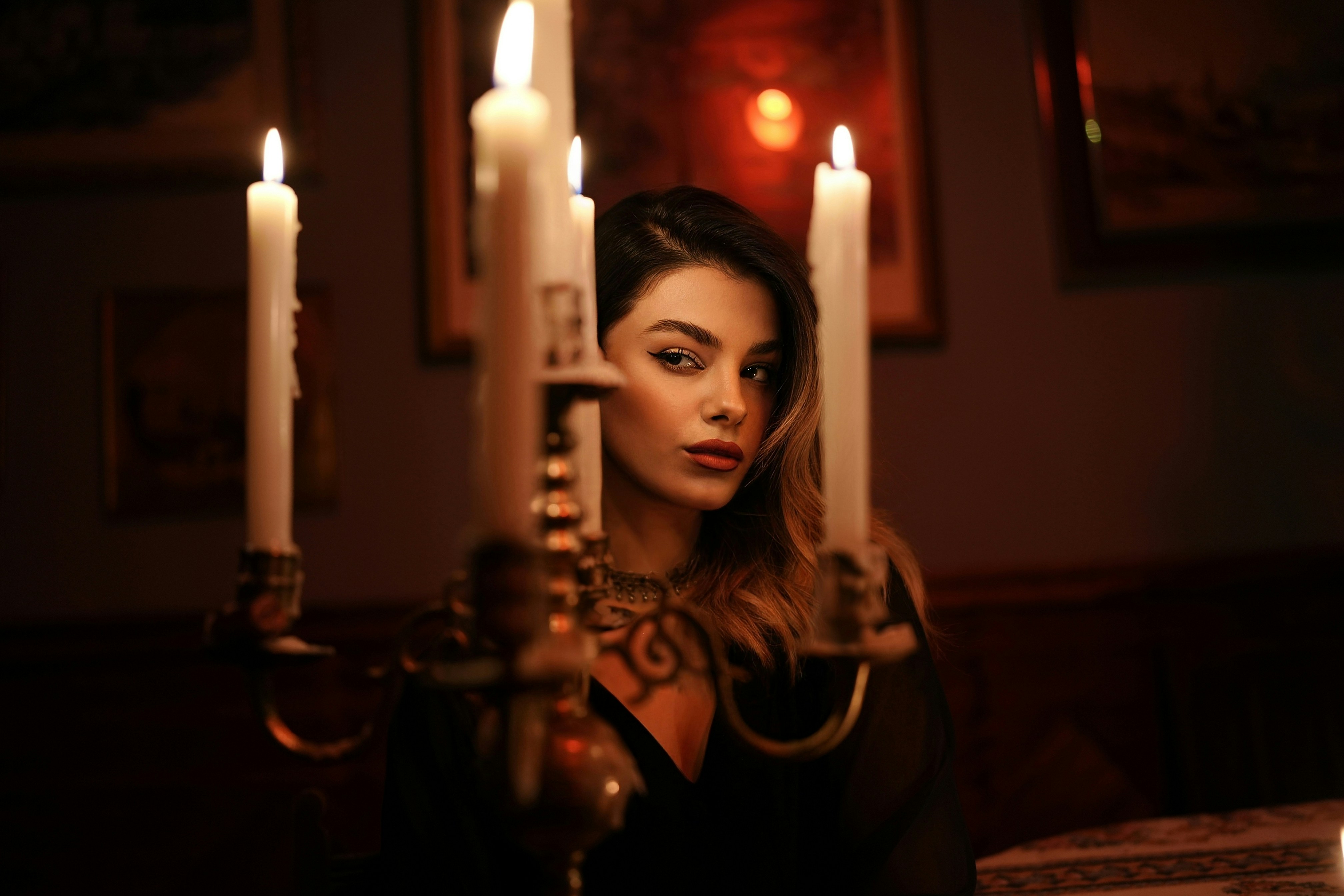A woman behind a lit candelabra in a dimly lit room