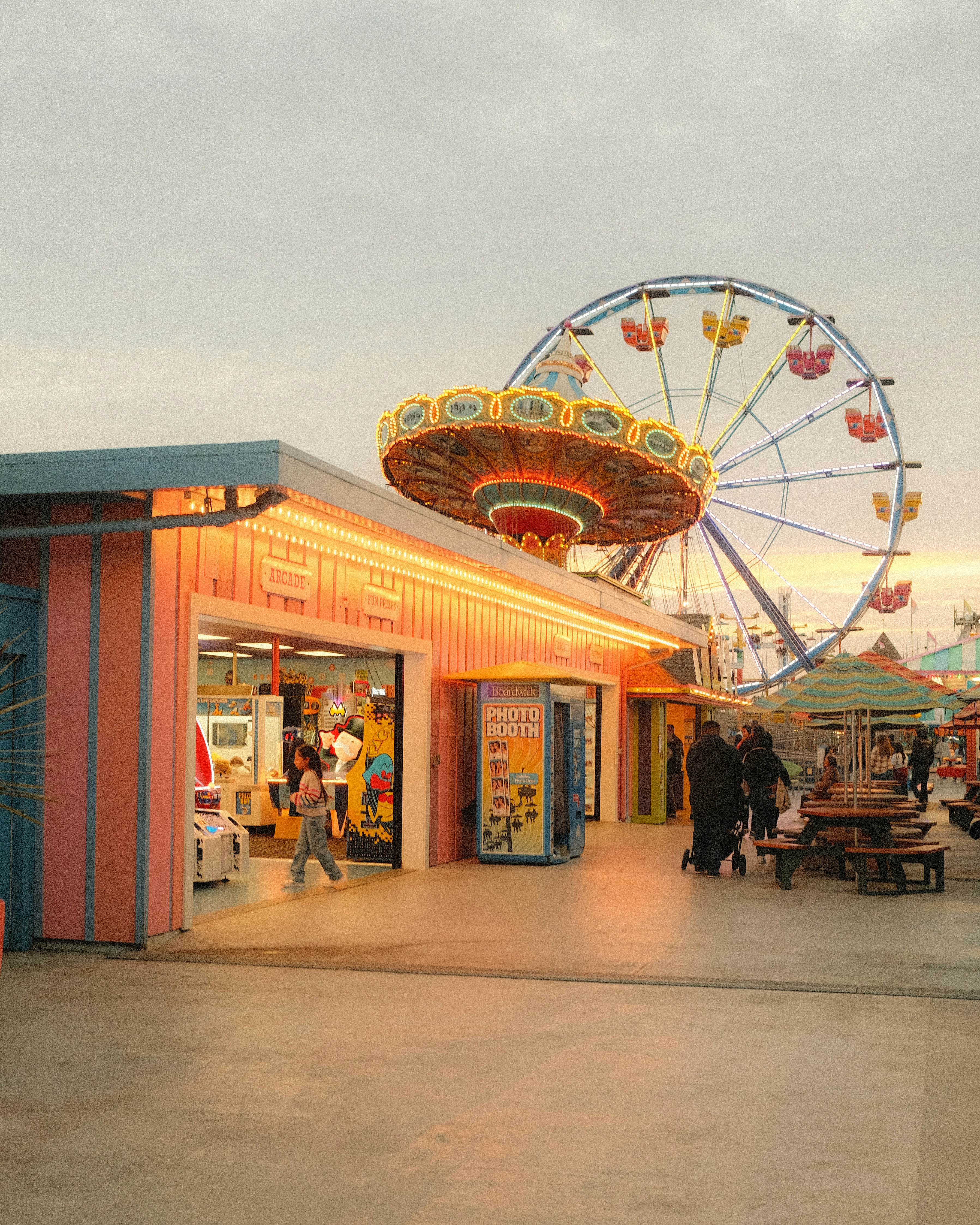 An amusement park arcade with illuminated carnival rides and a Ferris wheel