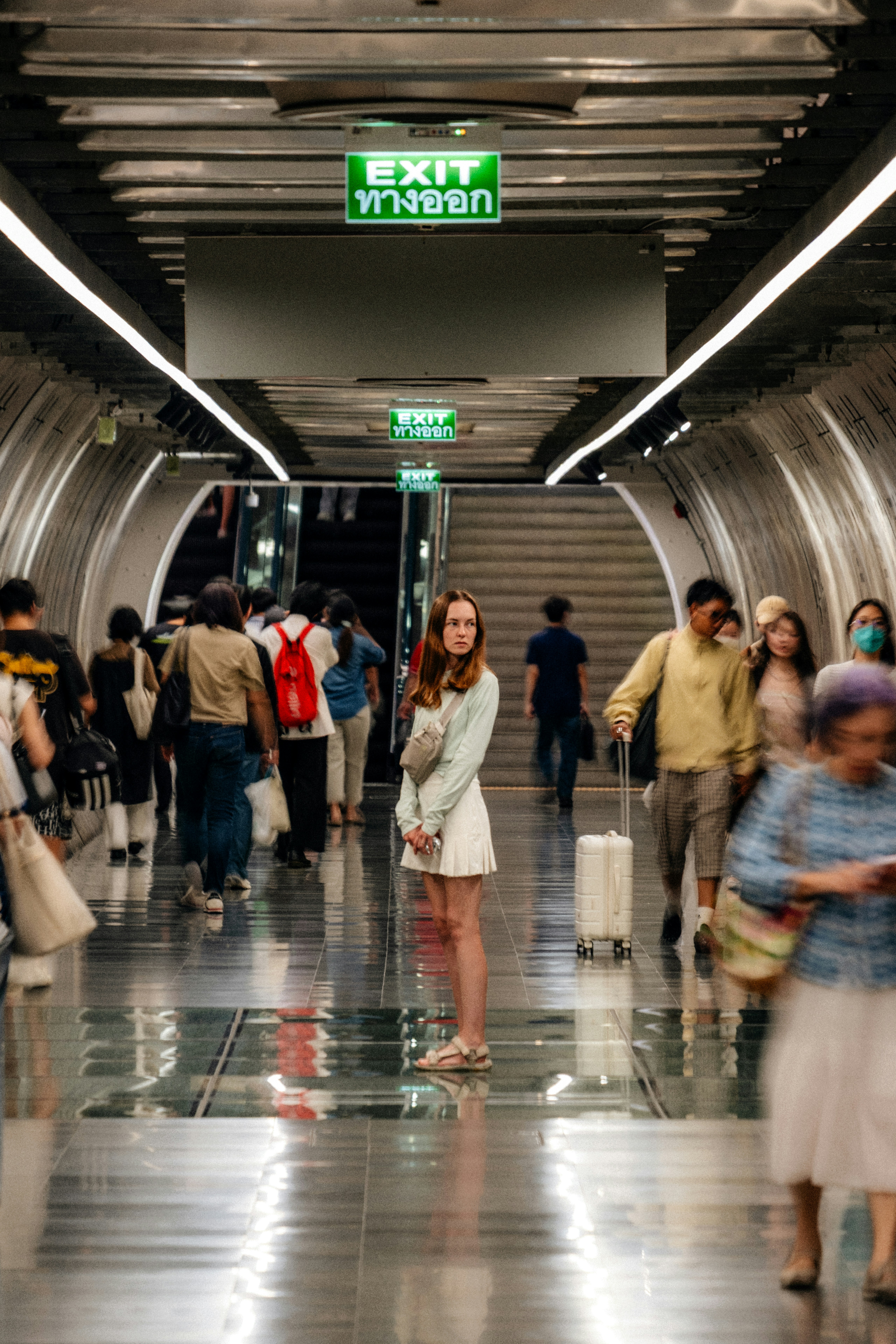 A woman in a light green top and white skirt in a subway station