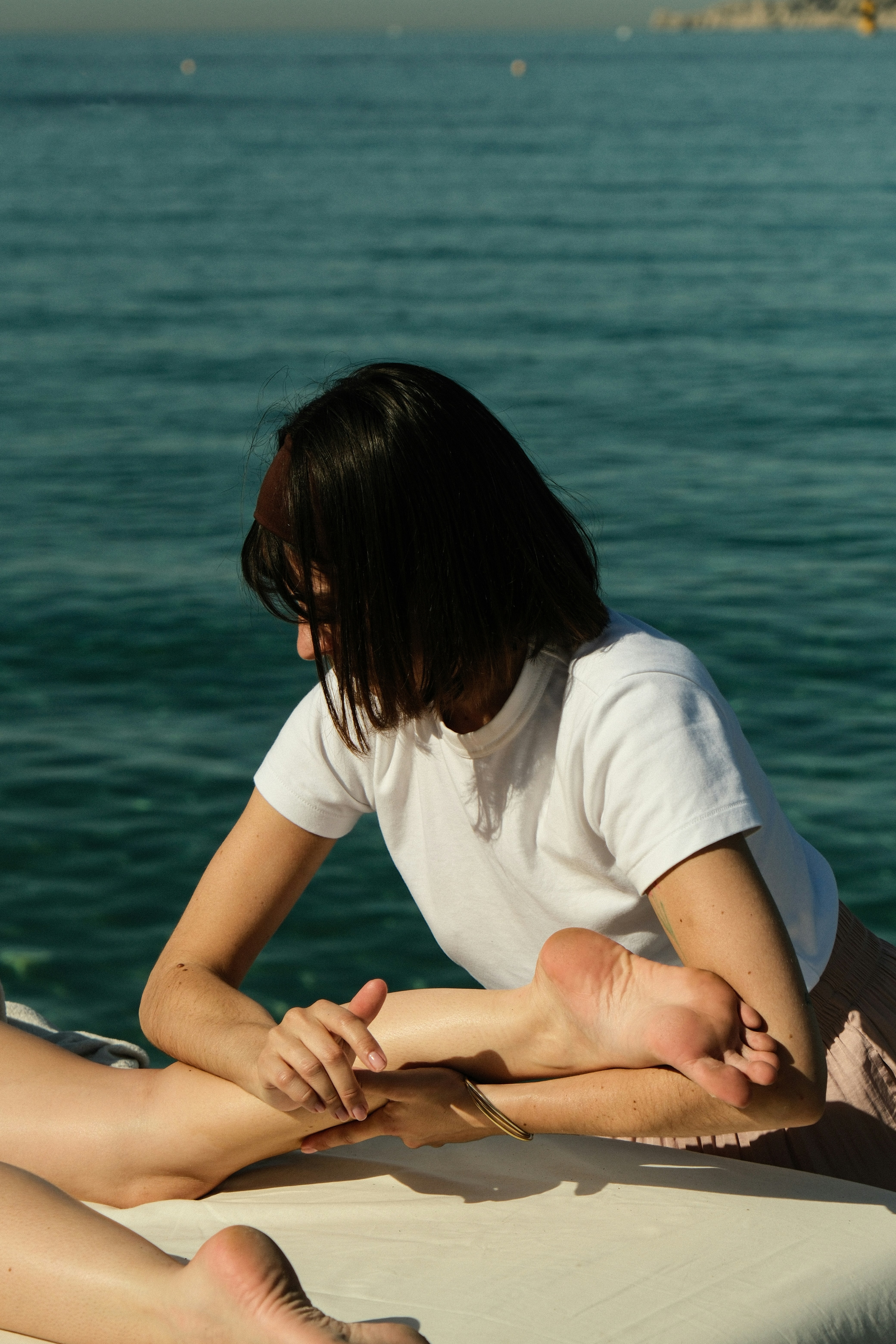 A practitioner massages a leg on a treatment table.