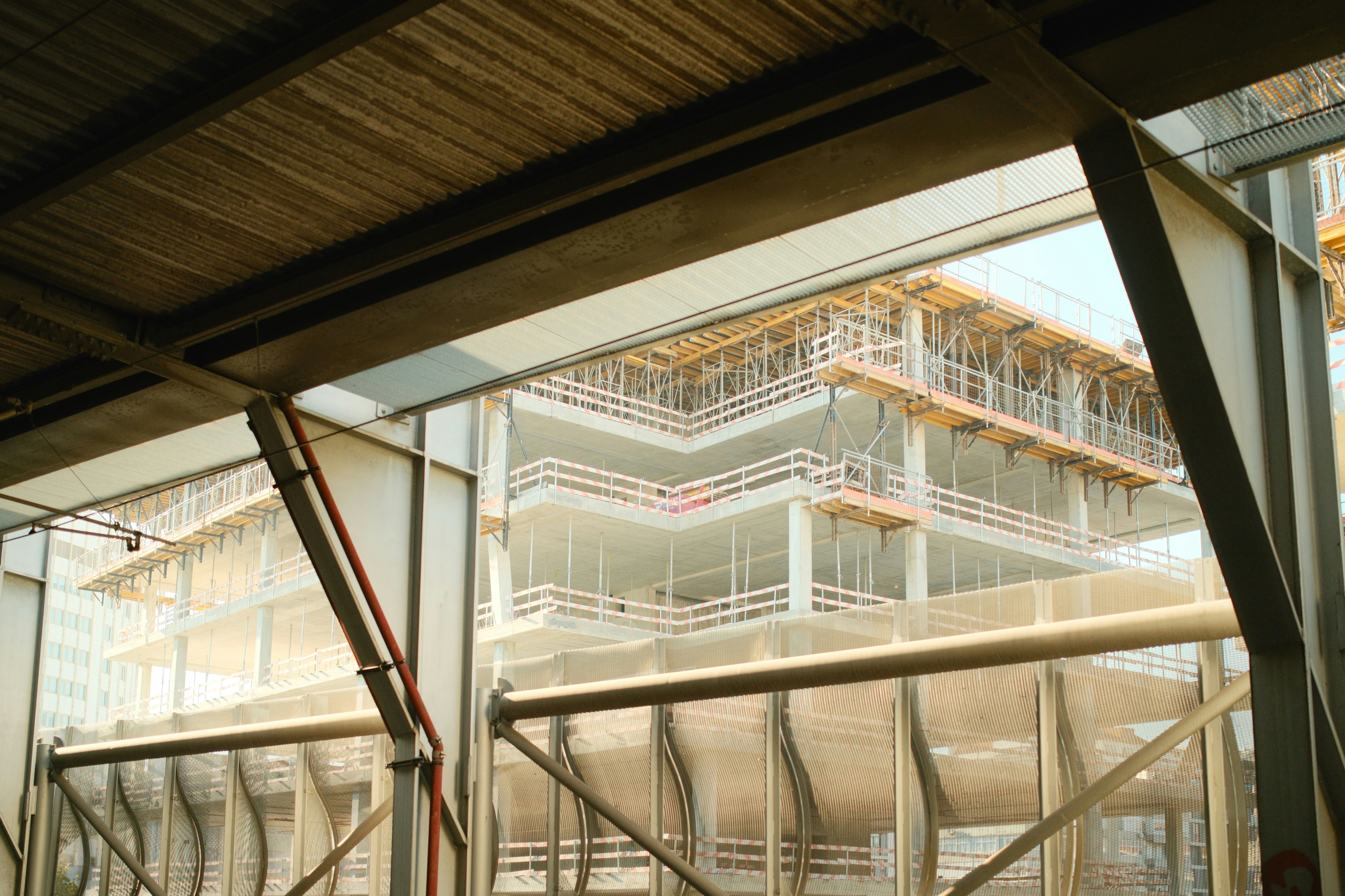 A multi-story building under construction with scaffolding and concrete floors viewed from inside