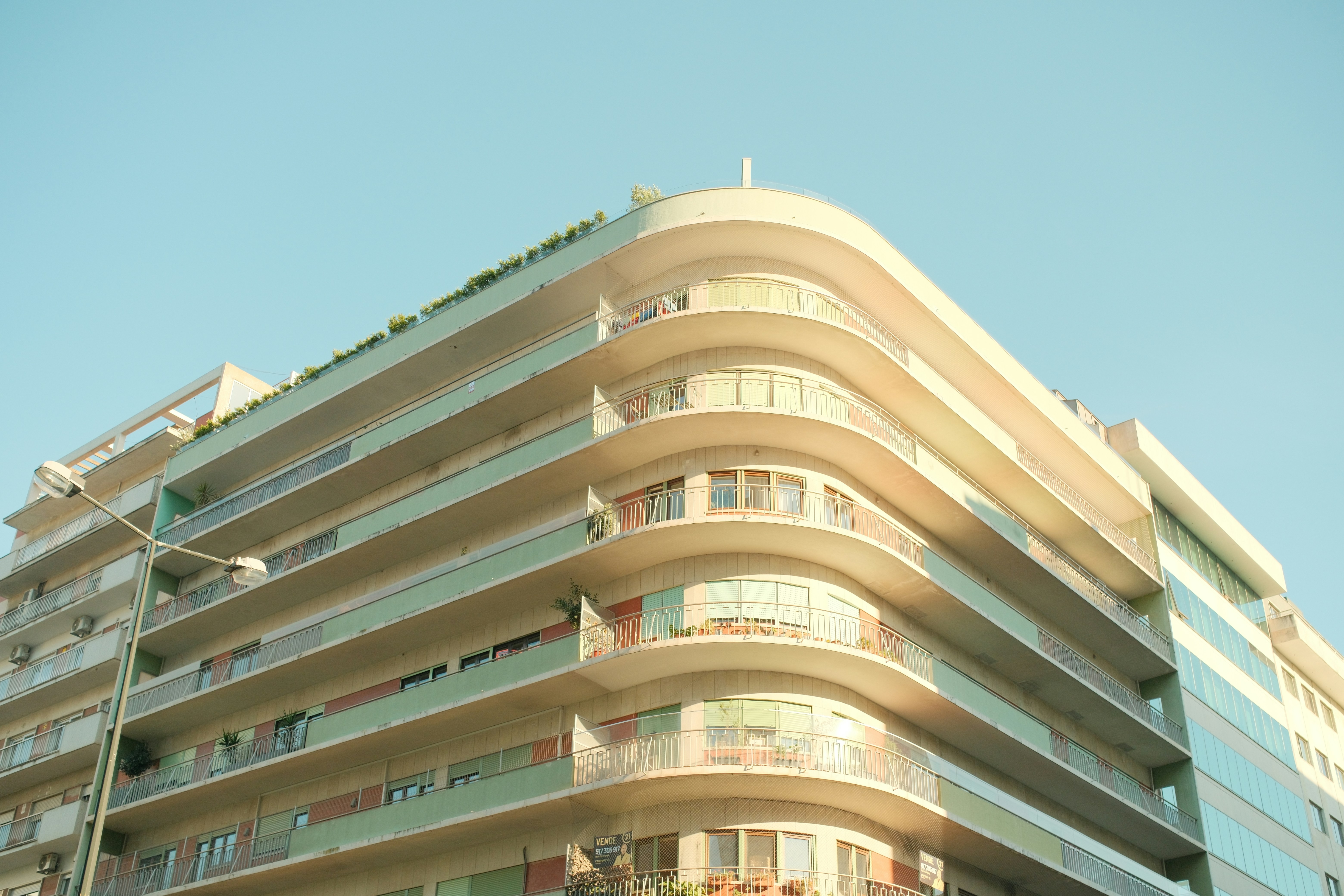 A curved corner of a modern apartment building with balconies against a clear sky