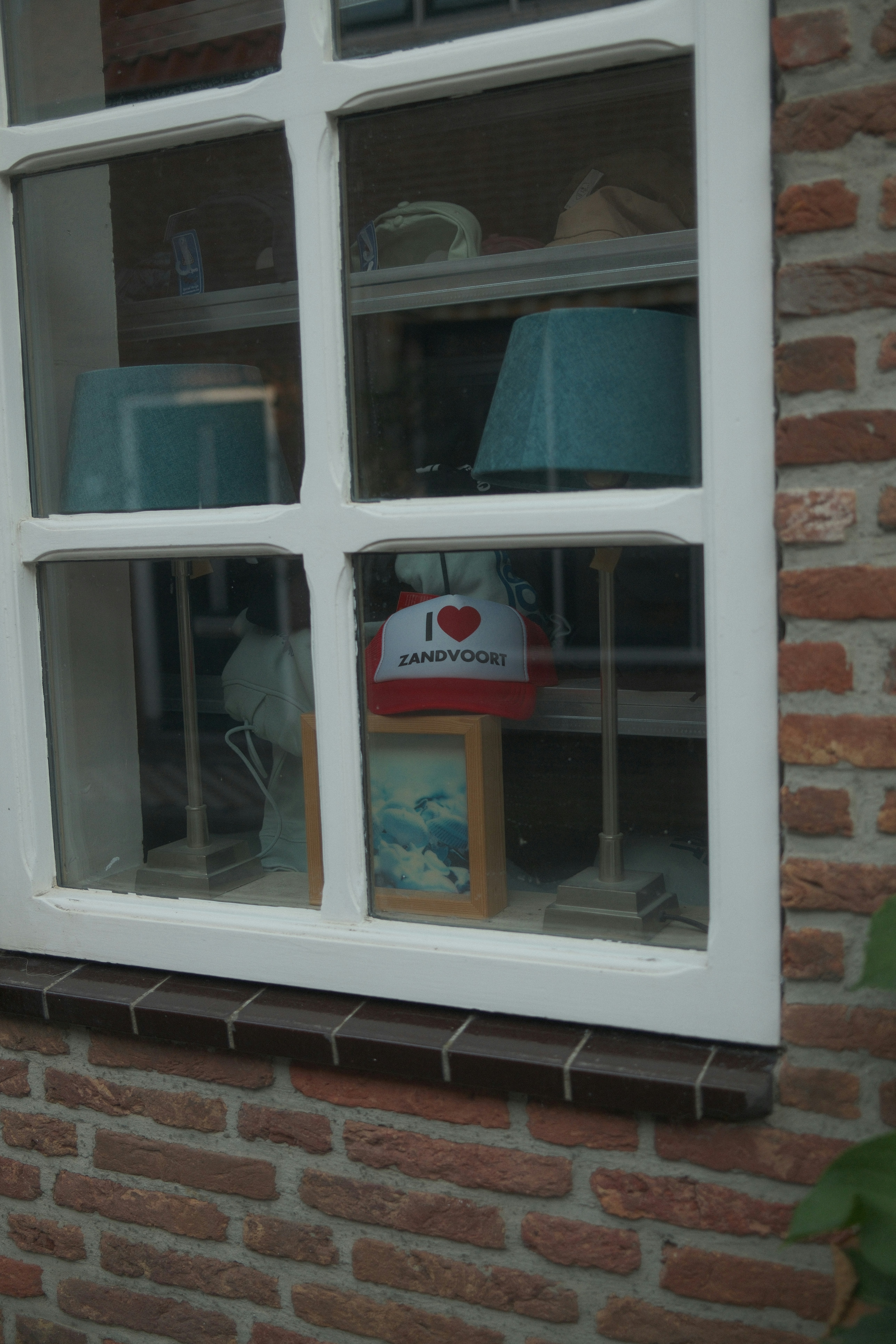 A shop window displaying two lamps and a cap reading I heart Zandvoort