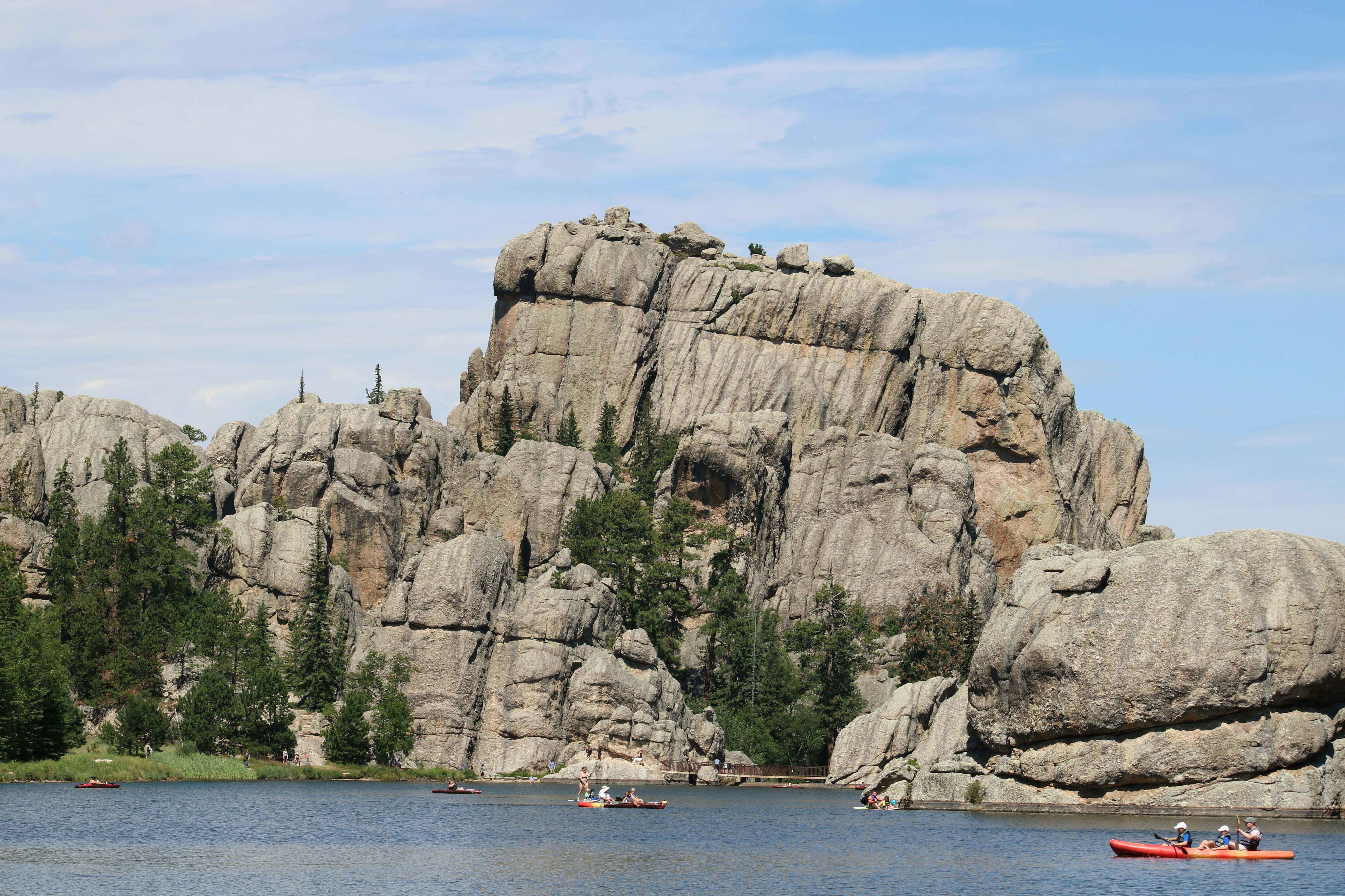 People in kayaks on a lake beneath towering granite rock formations