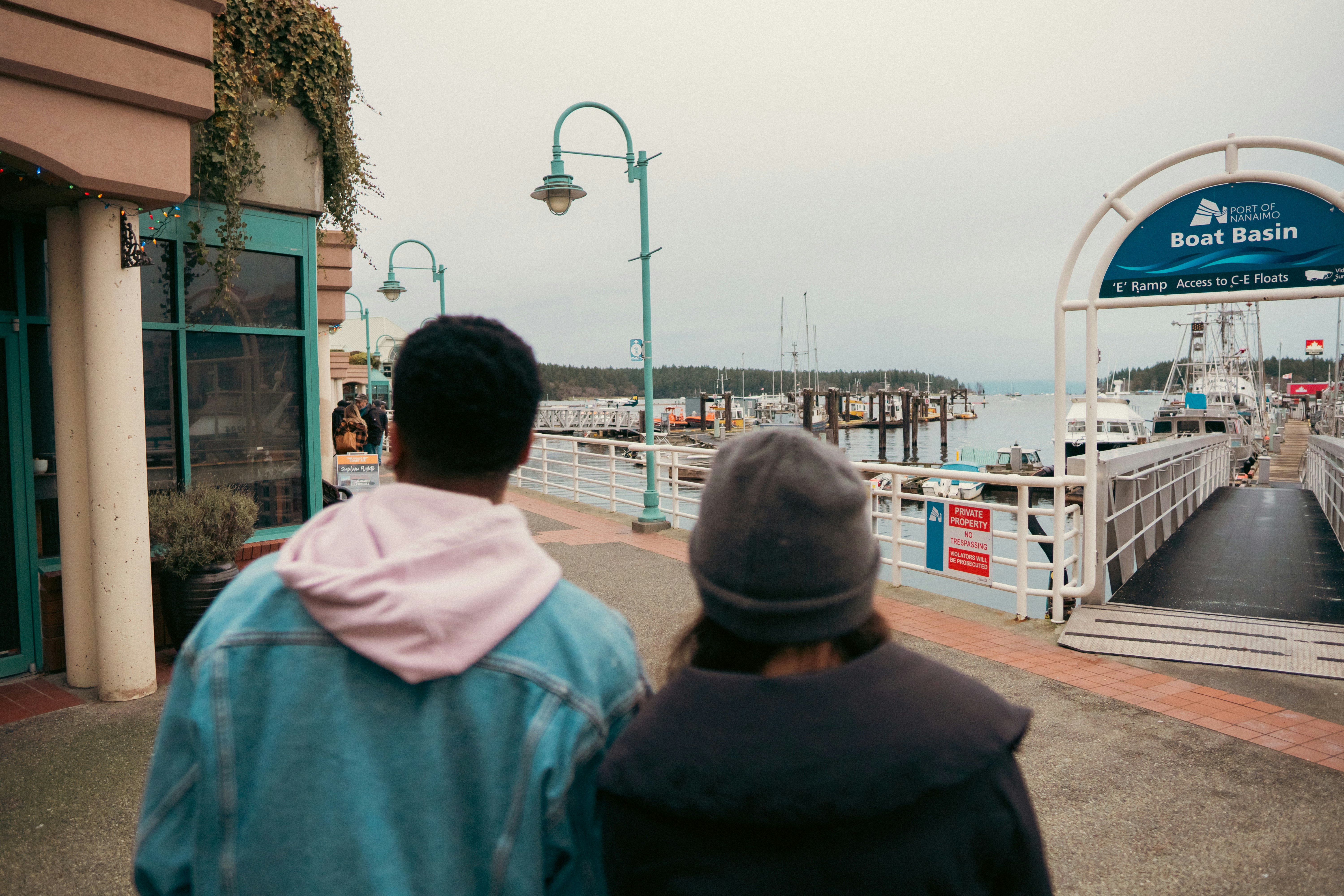 Two people walking toward the Port of Nanaimo Boat Basin on a cloudy day