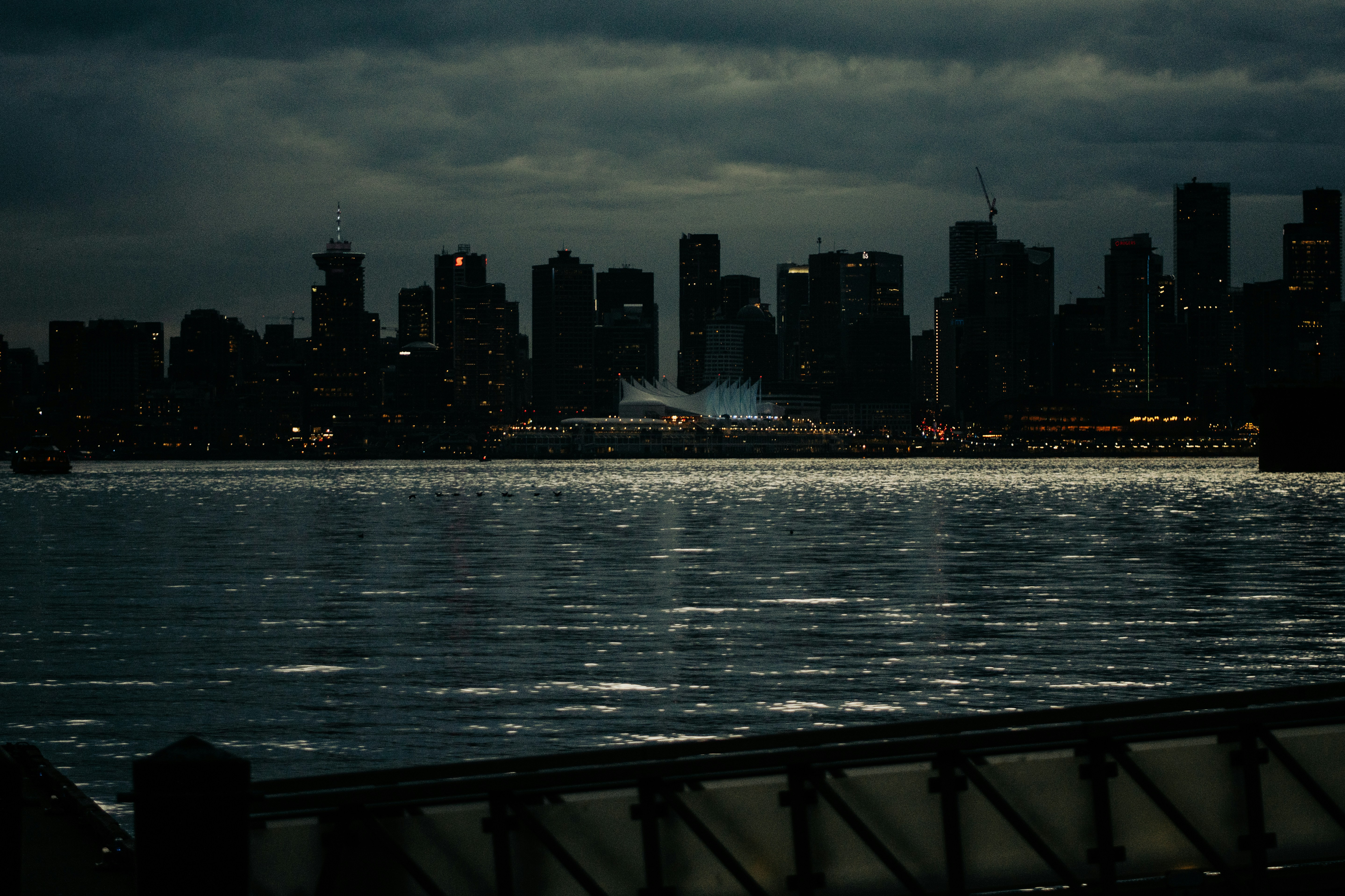 The Vancouver skyline at night across the dark water of the harbor