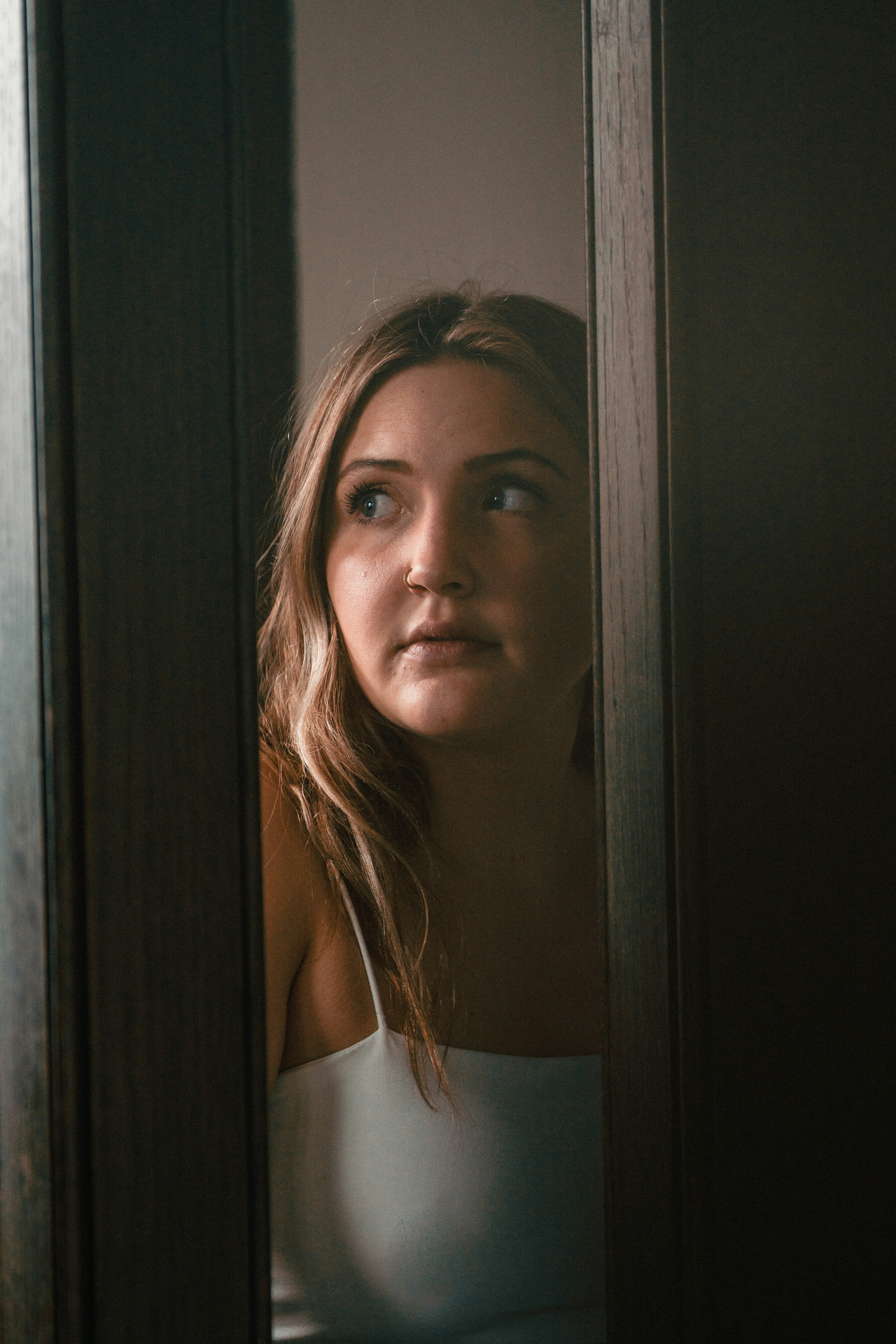 A woman in a white top looking through a narrow doorway