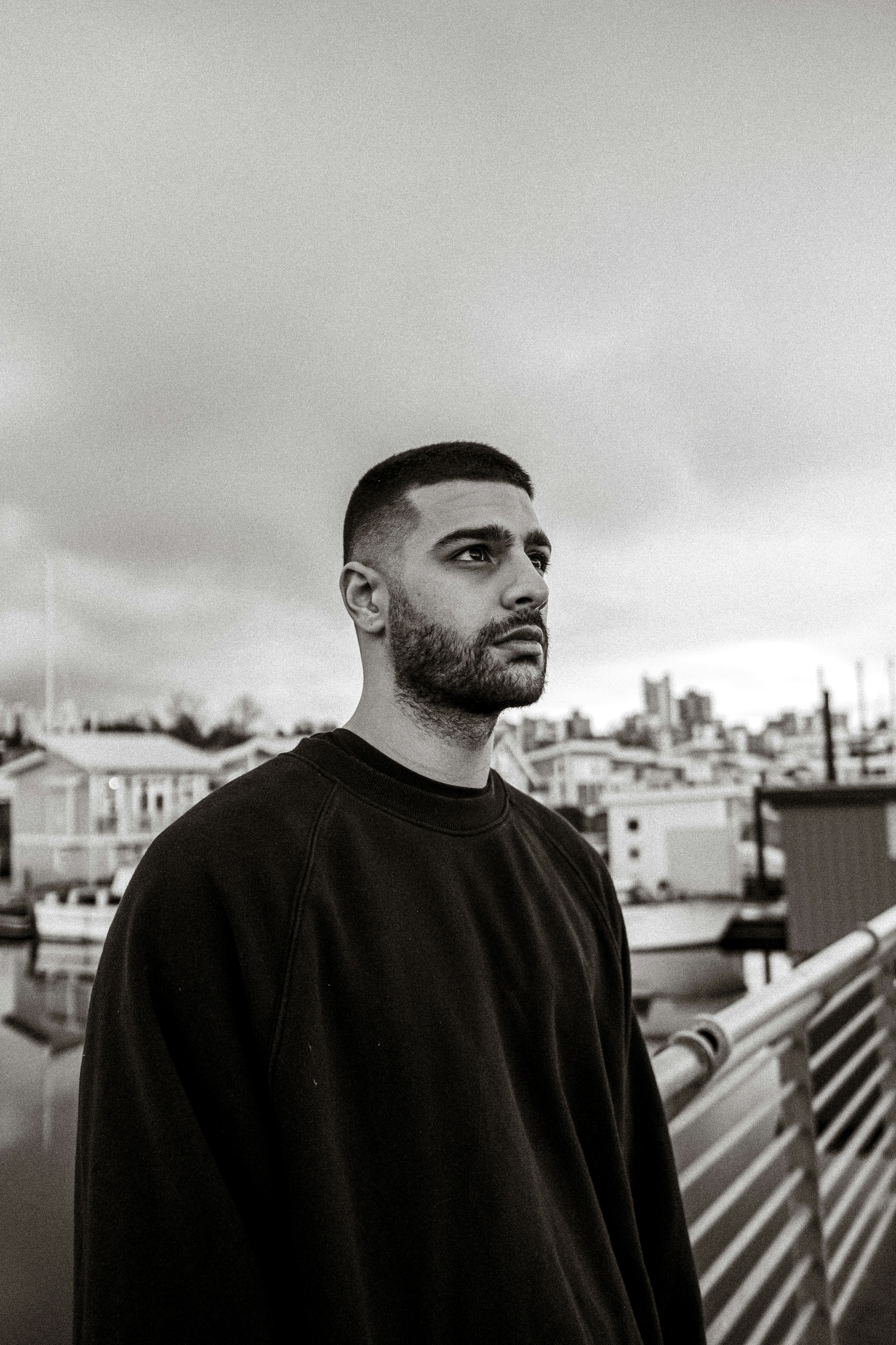 A man with a short haircut and beard in a black sweatshirt outdoors