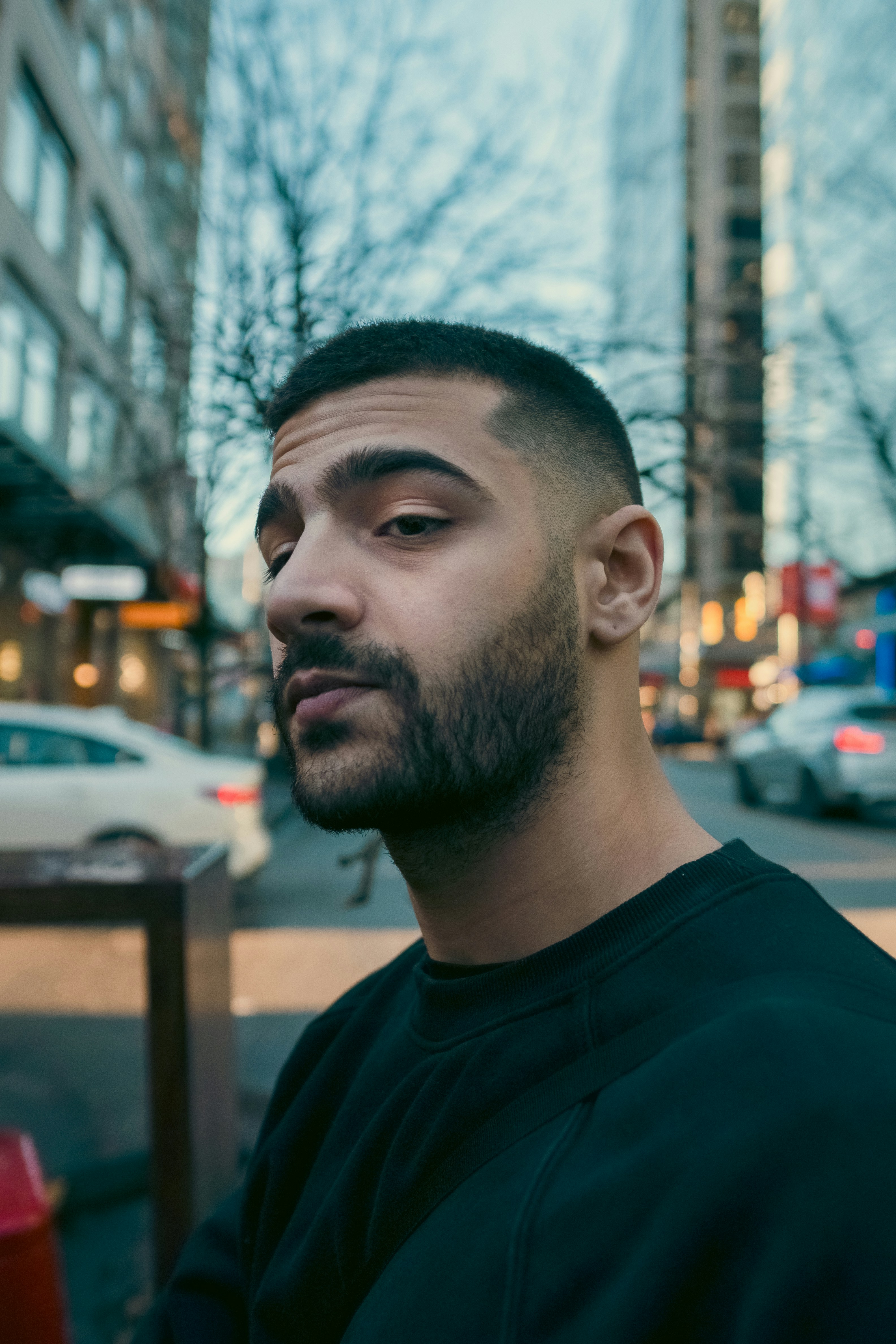 A man with a short beard and faded haircut in a black sweatshirt