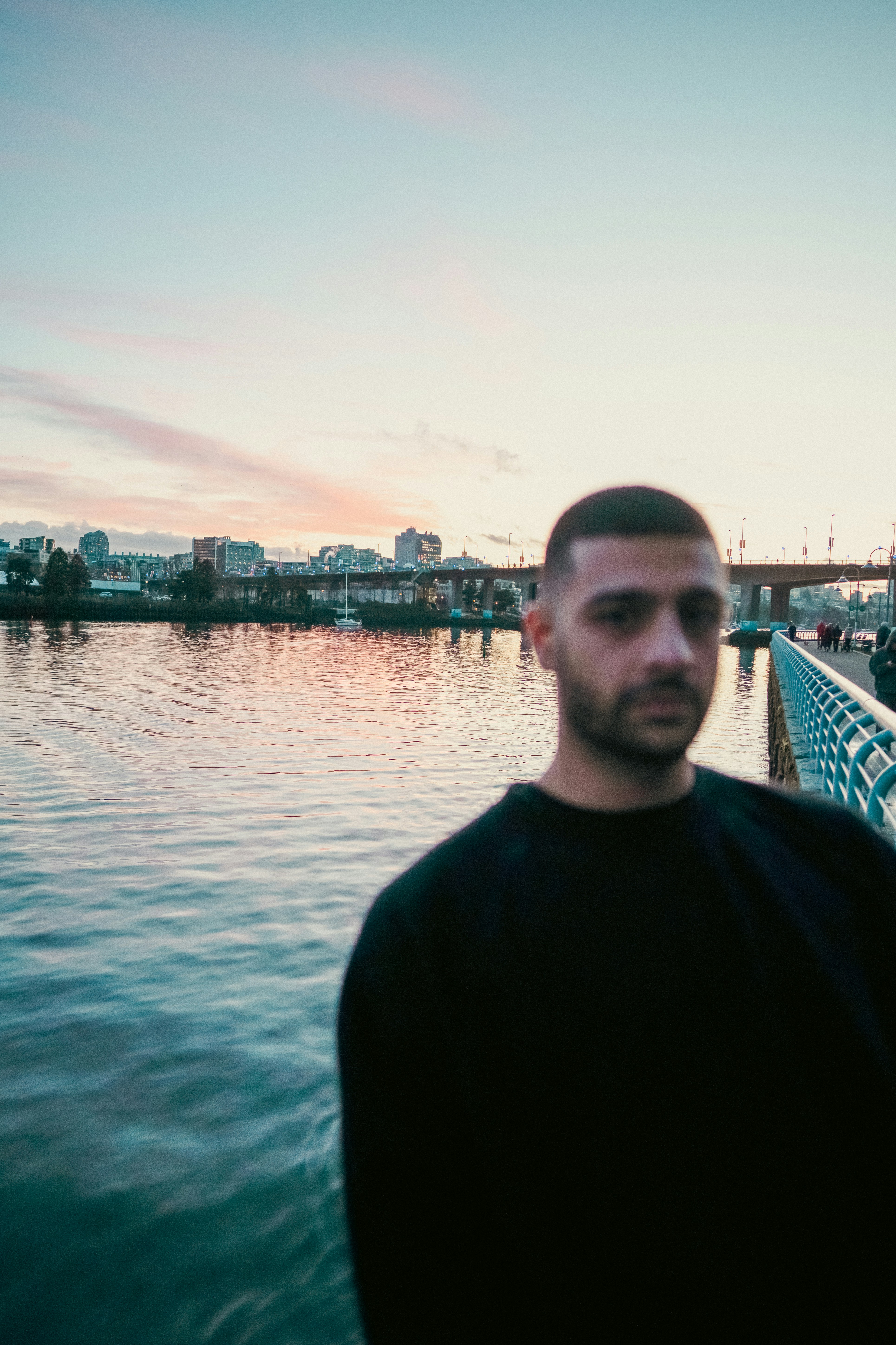 A man in a black shirt on a waterfront path at golden hour