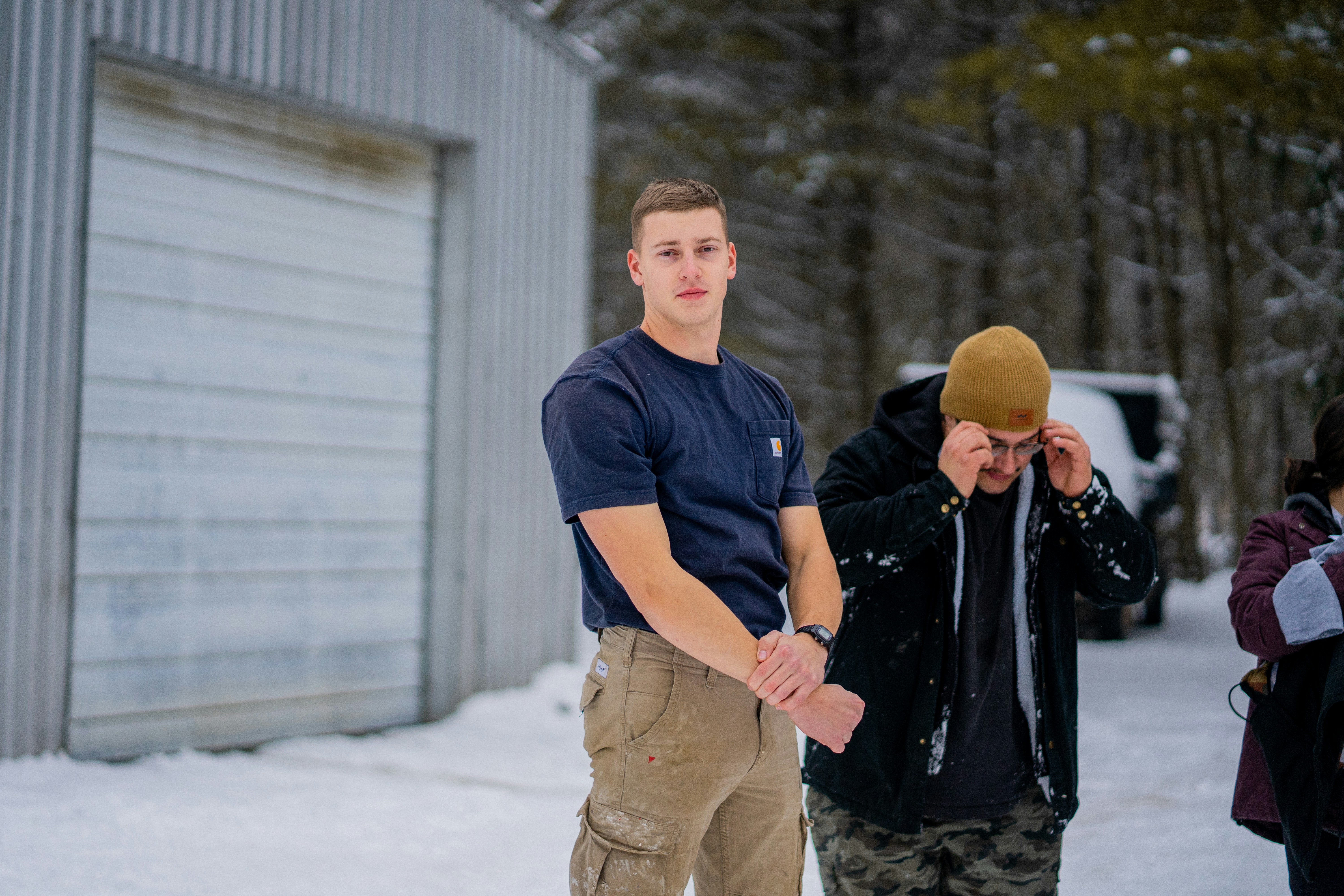 A man in a navy t-shirt and khaki pants outdoors in the snow