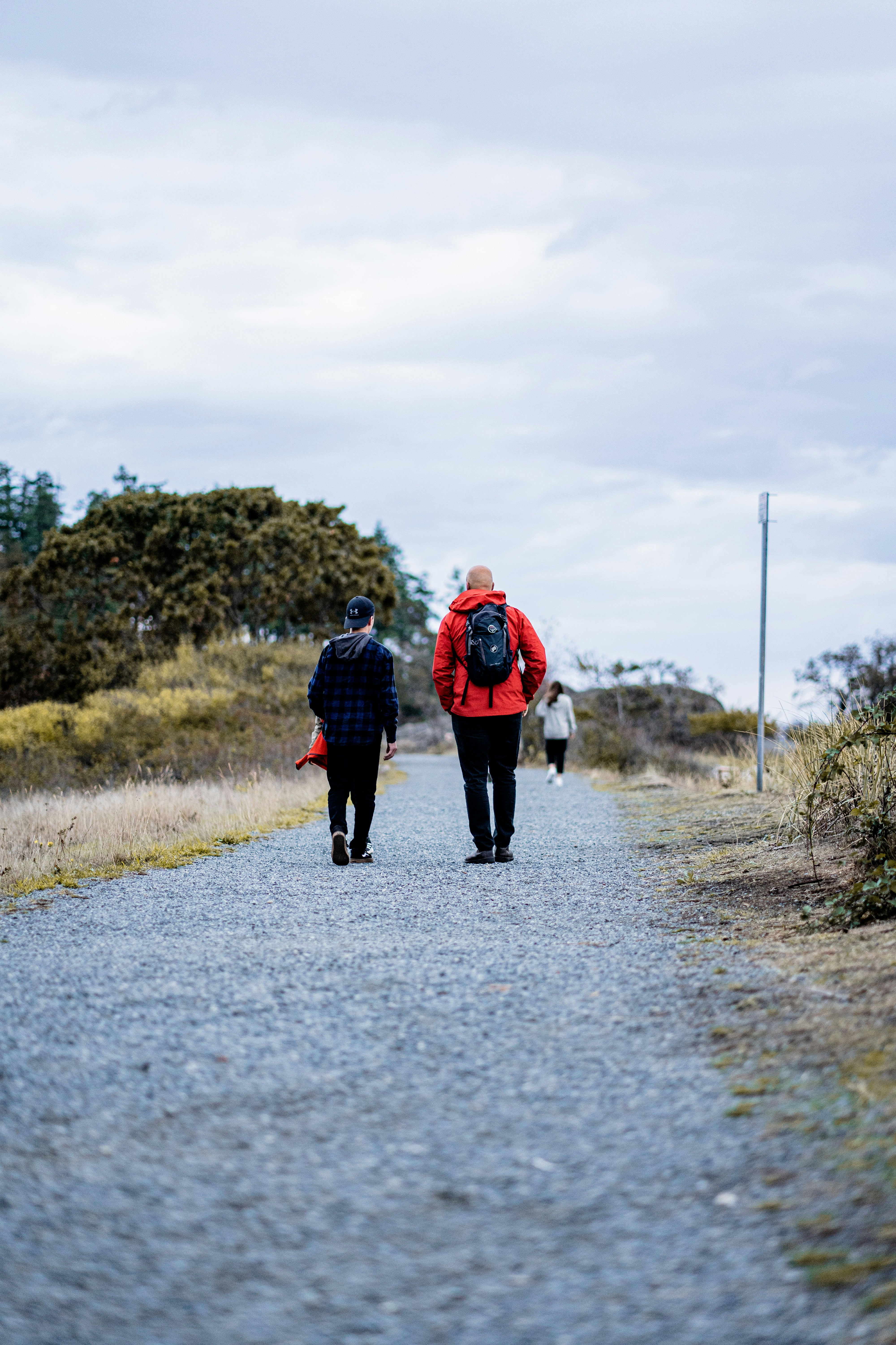 Two people walking along a gravel path through a grassy landscape