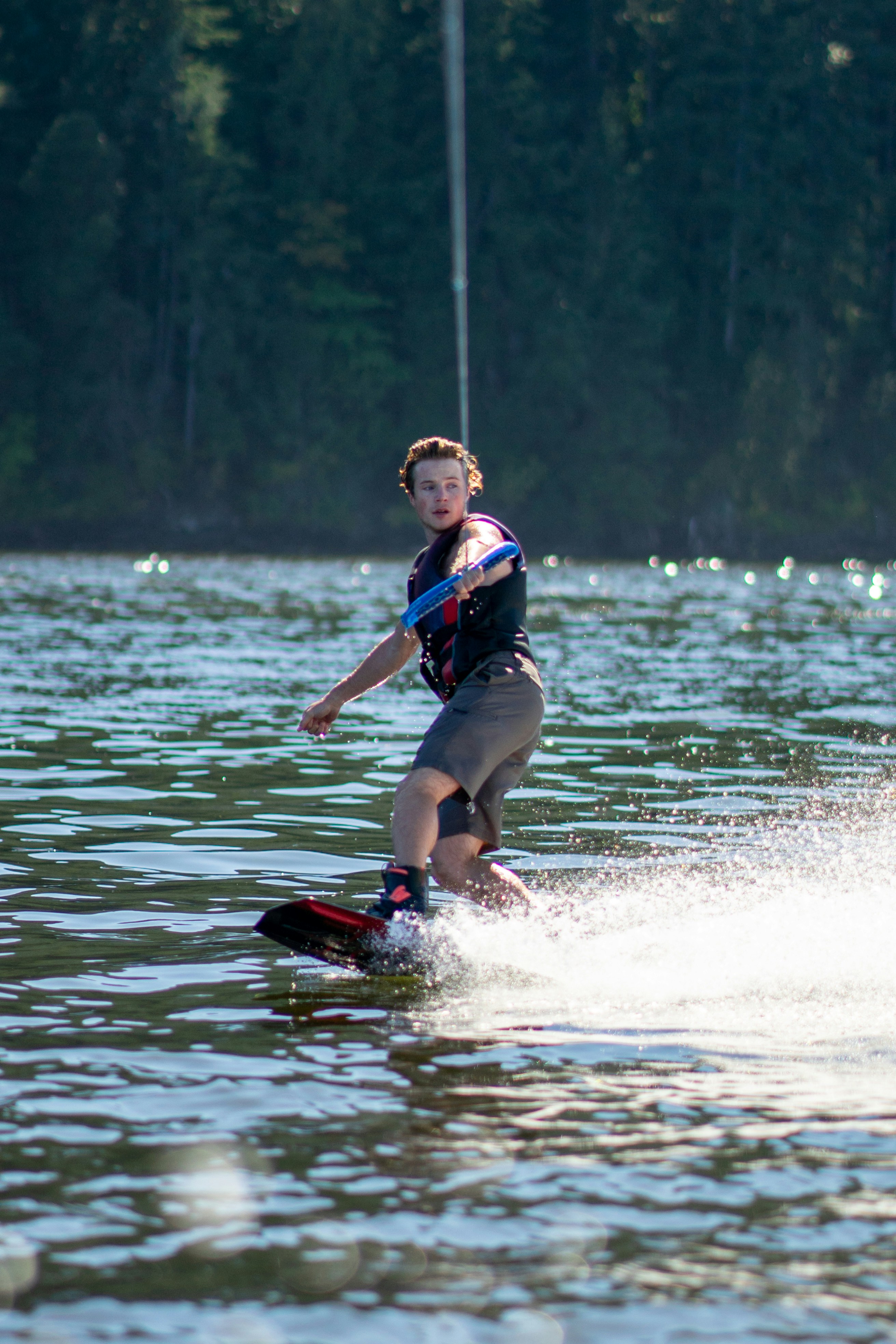 A man wakeboarding on a lake with a forest in the background