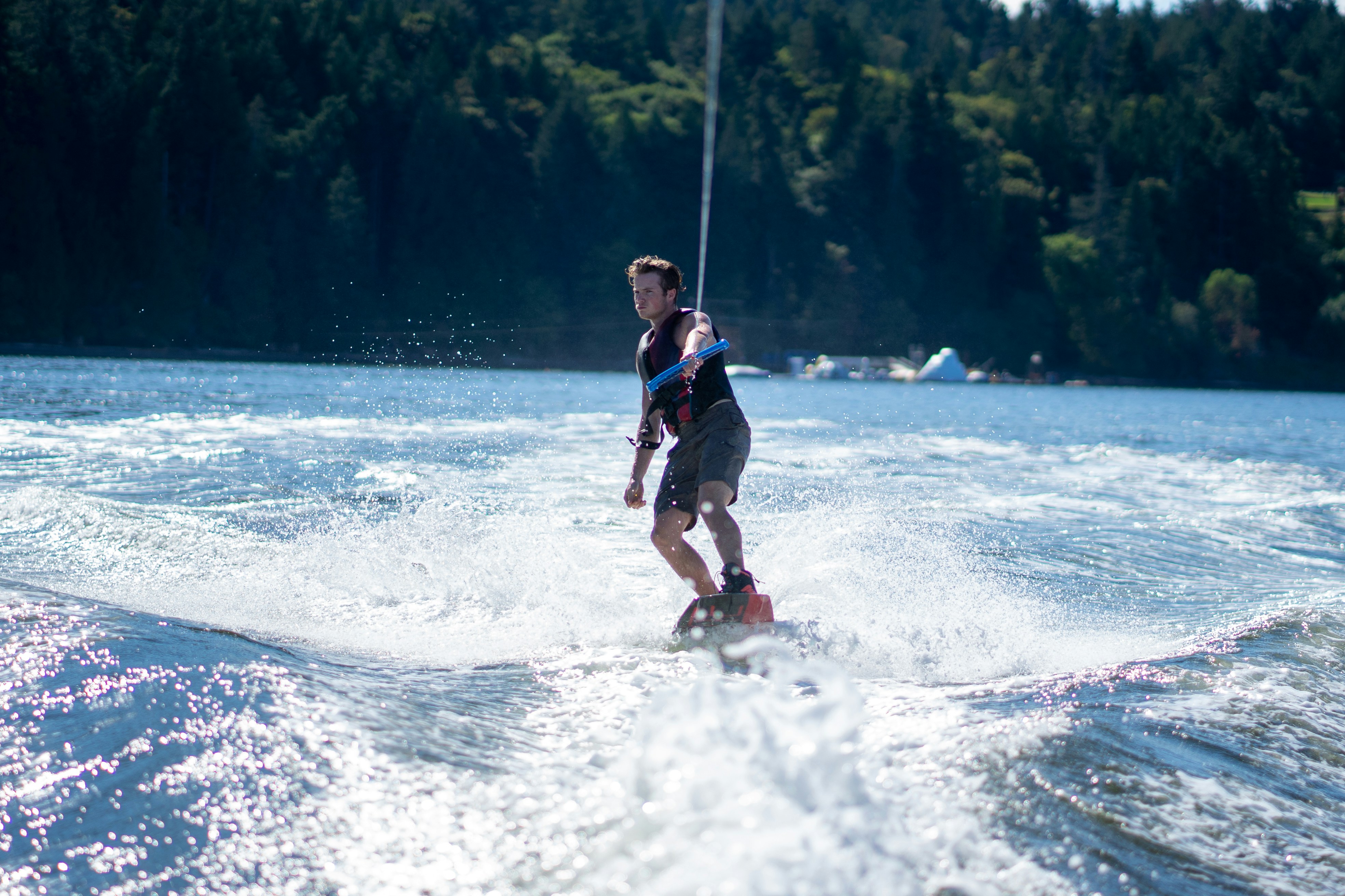 A man wakeboarding on a lake with a dense forest in the background