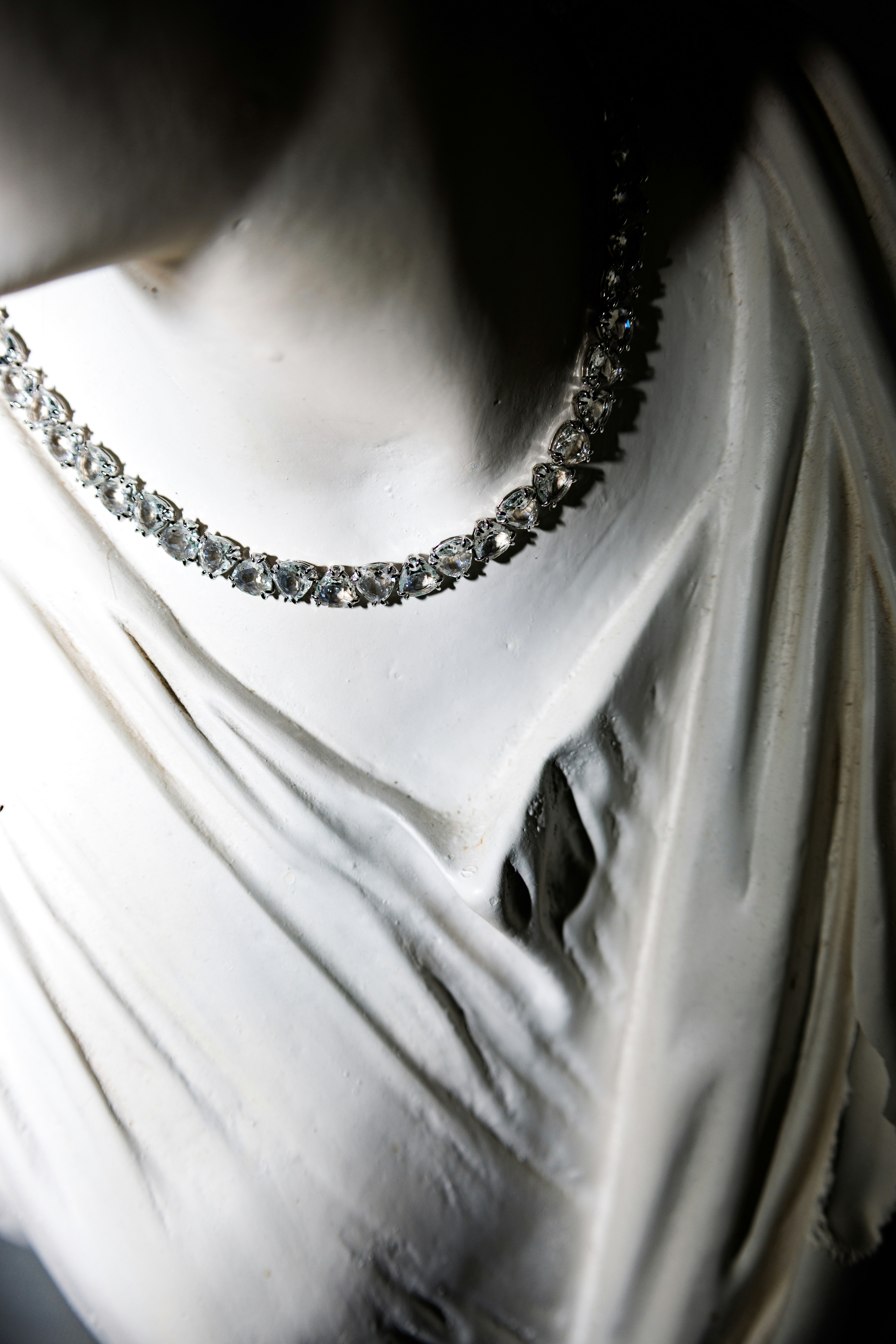 A sparkling diamond necklace around the neck of a white plaster classical statue