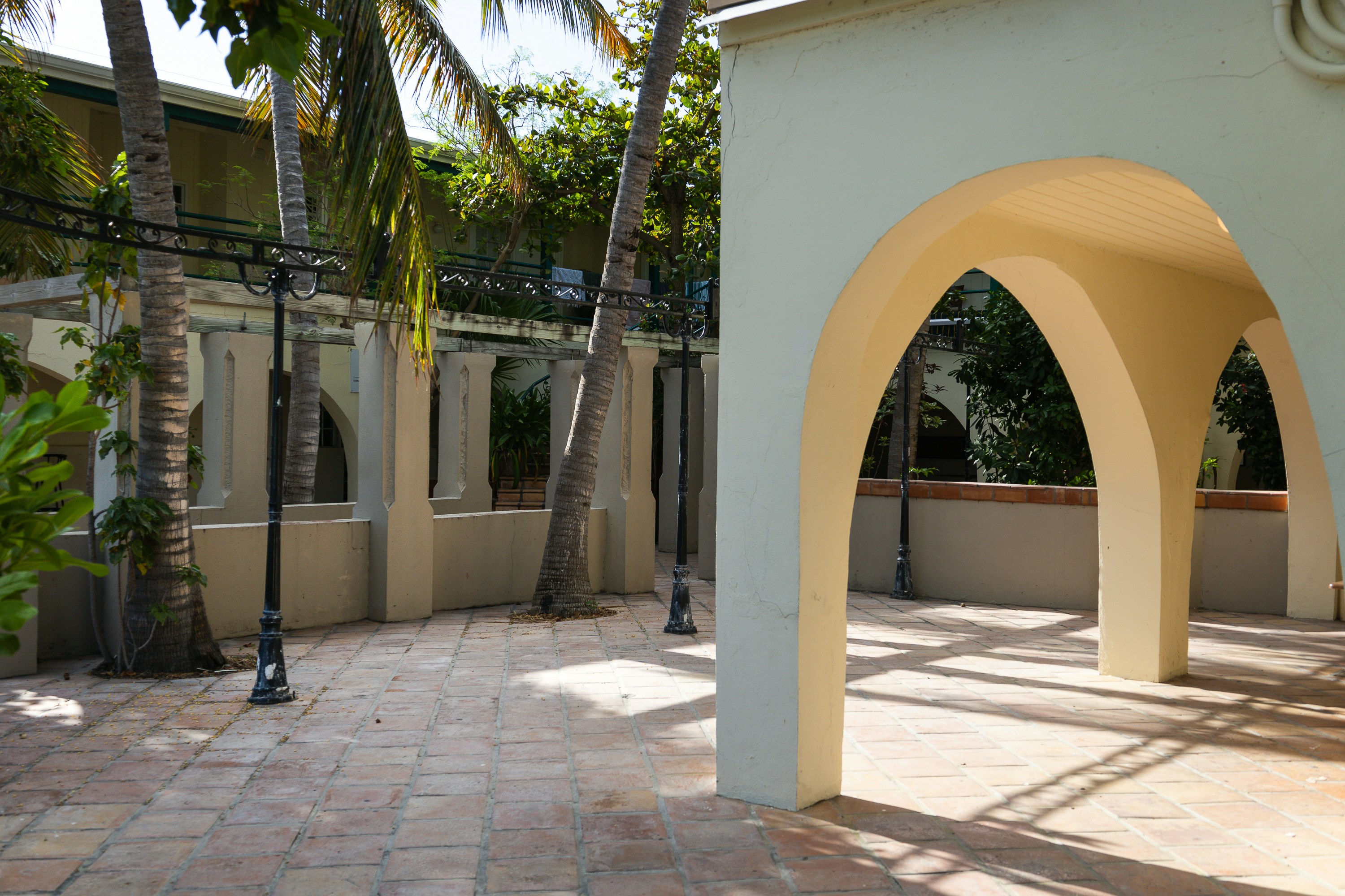 Un cortile piastrellato con colonne ad arco e palme sotto la luce intensa del sole