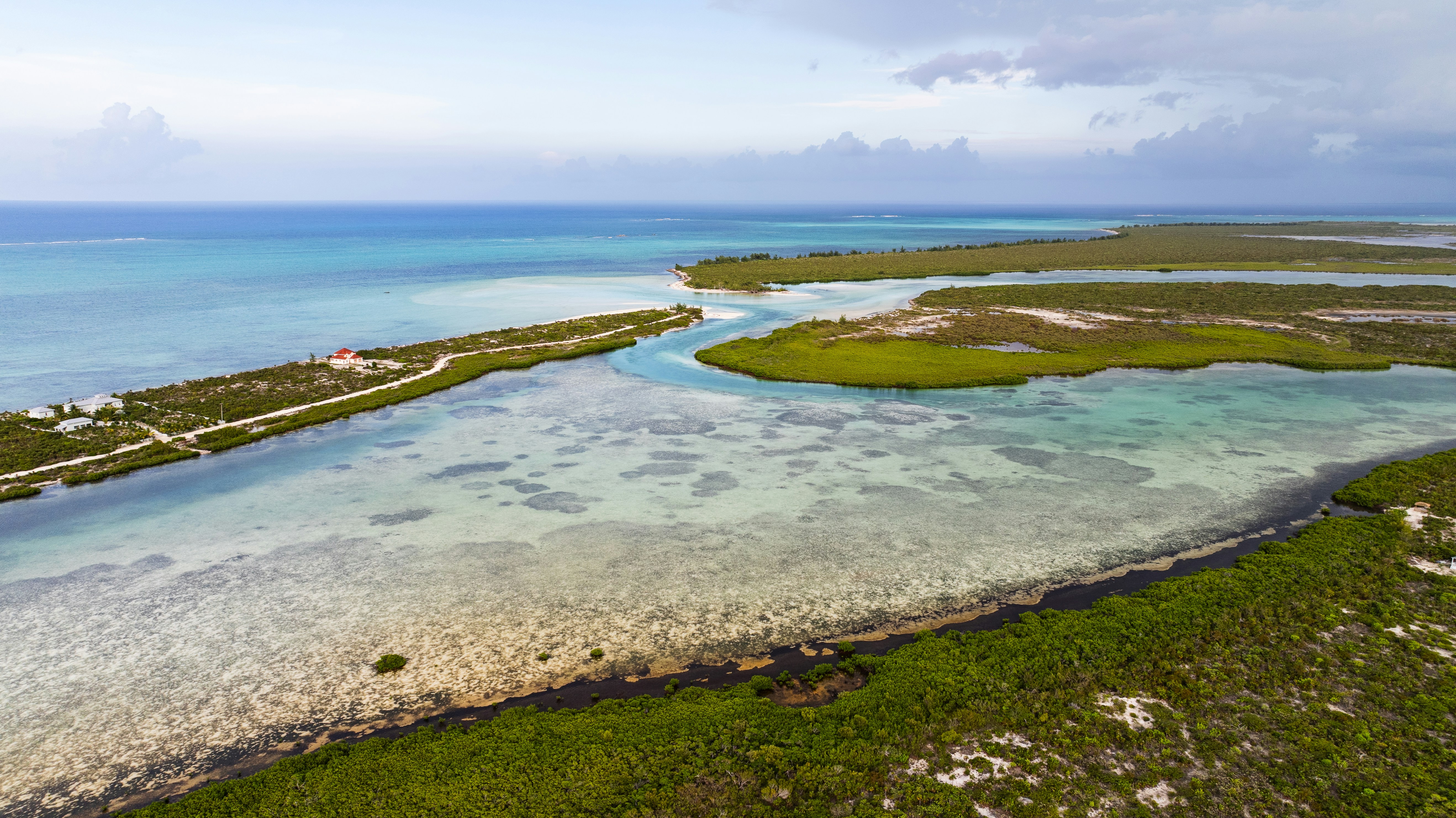 Aerial view of a turquoise lagoon with mangrove islands and a narrow sandy path