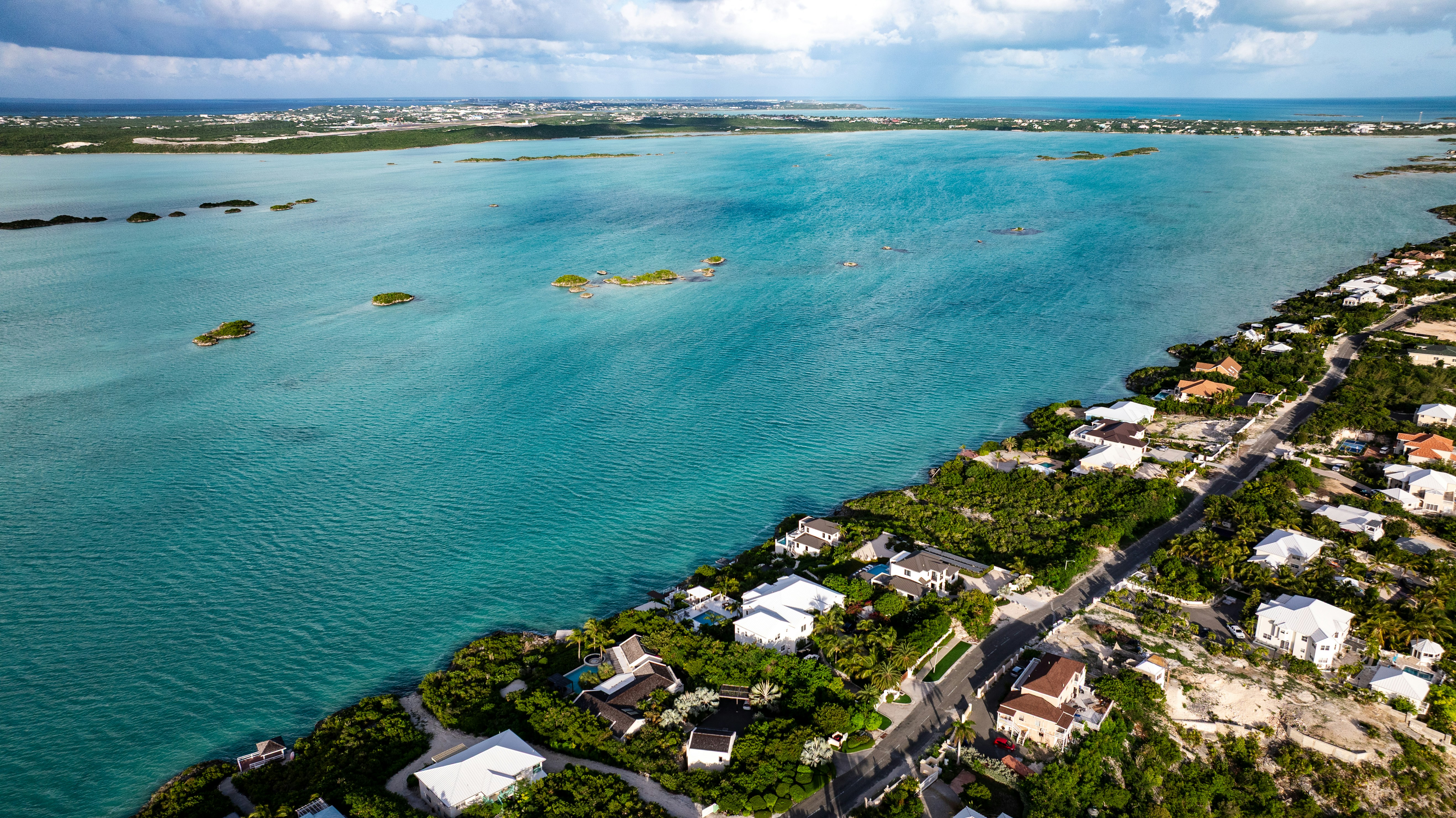 Aerial view of a turquoise bay with small islands and coastal houses