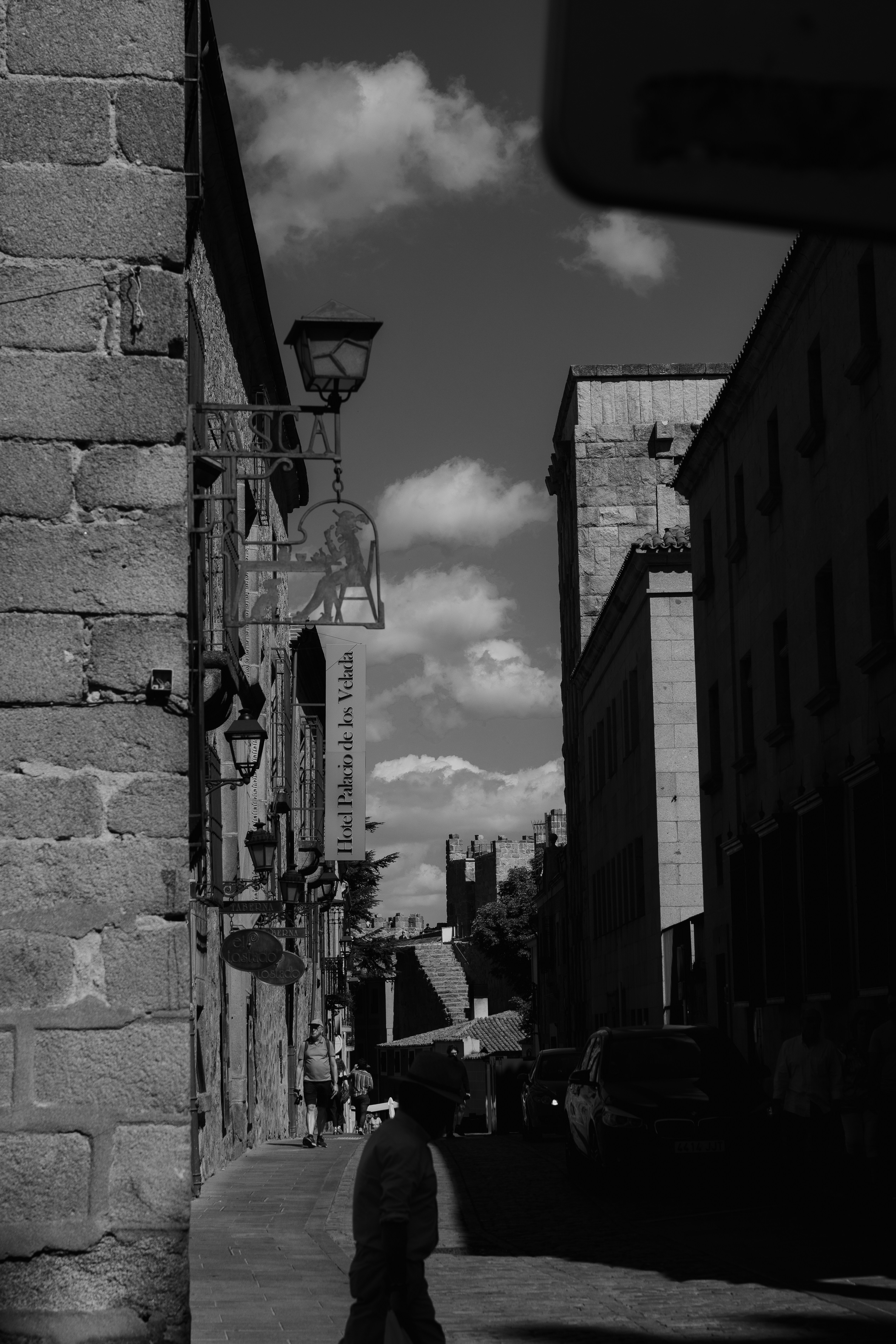 A narrow stone street in Avila with a sign for Hotel Palacio de los Velada