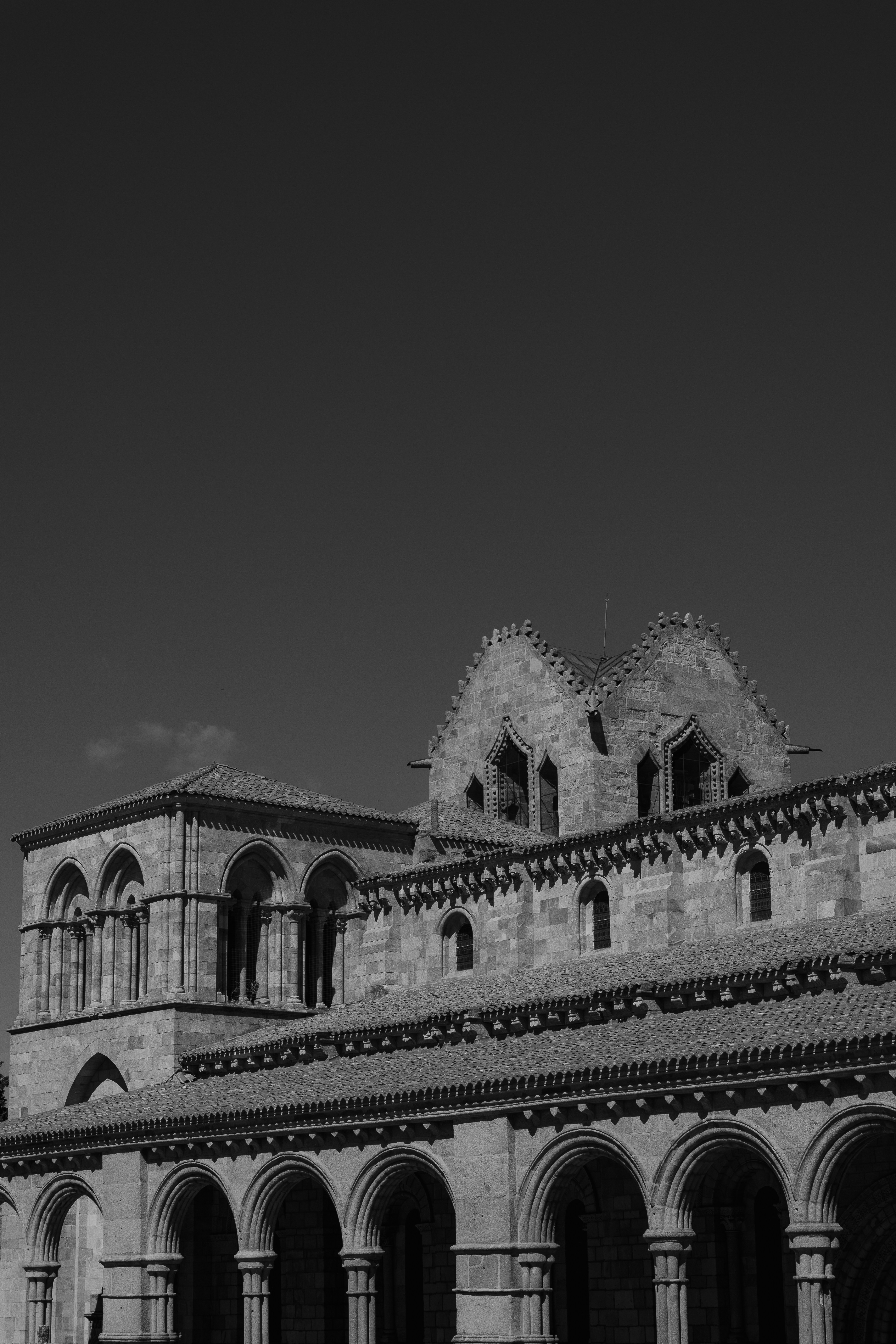 A Romanesque stone church with arched windows and a tiled roof