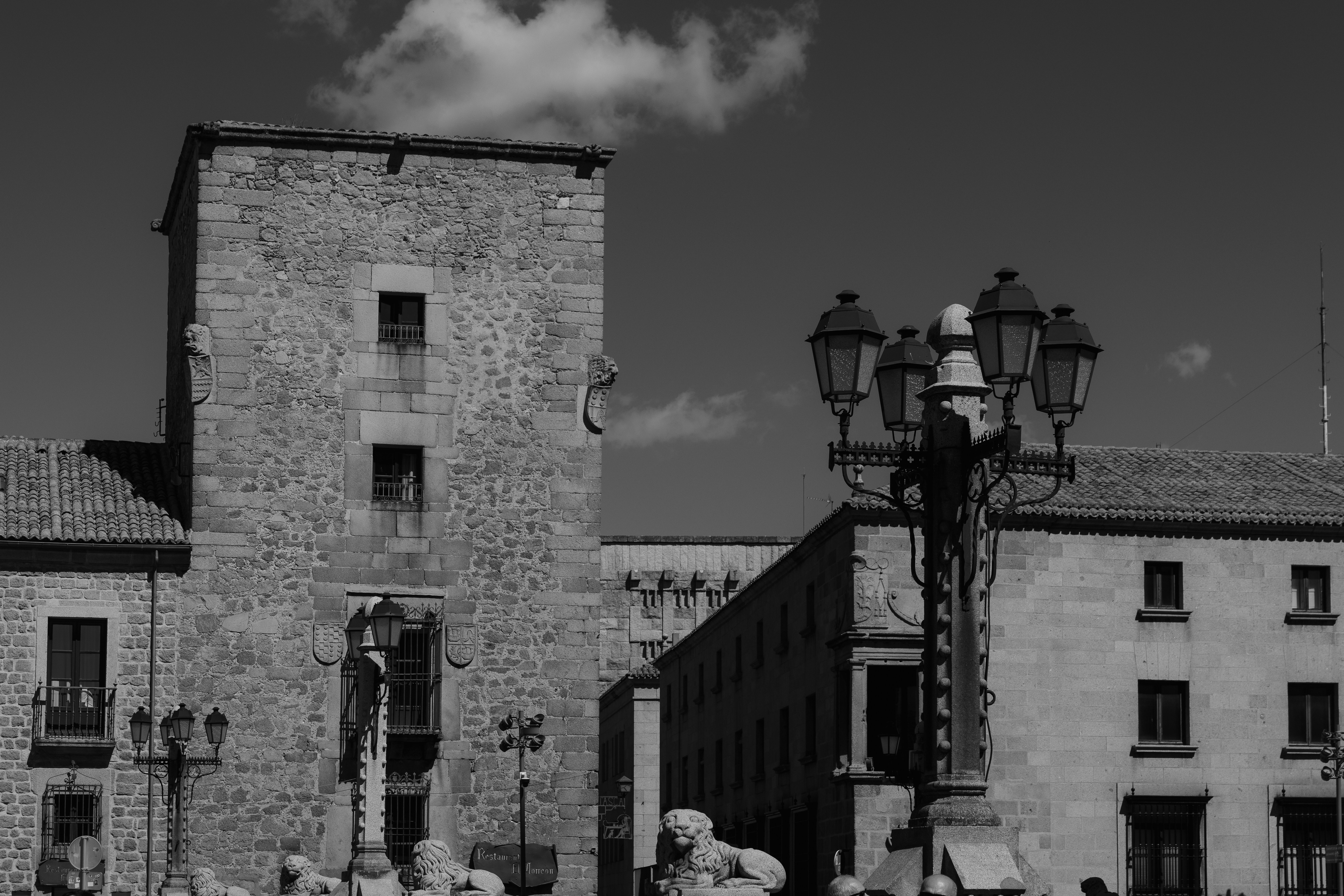 A stone tower and historic buildings with ornate street lamps in a city square