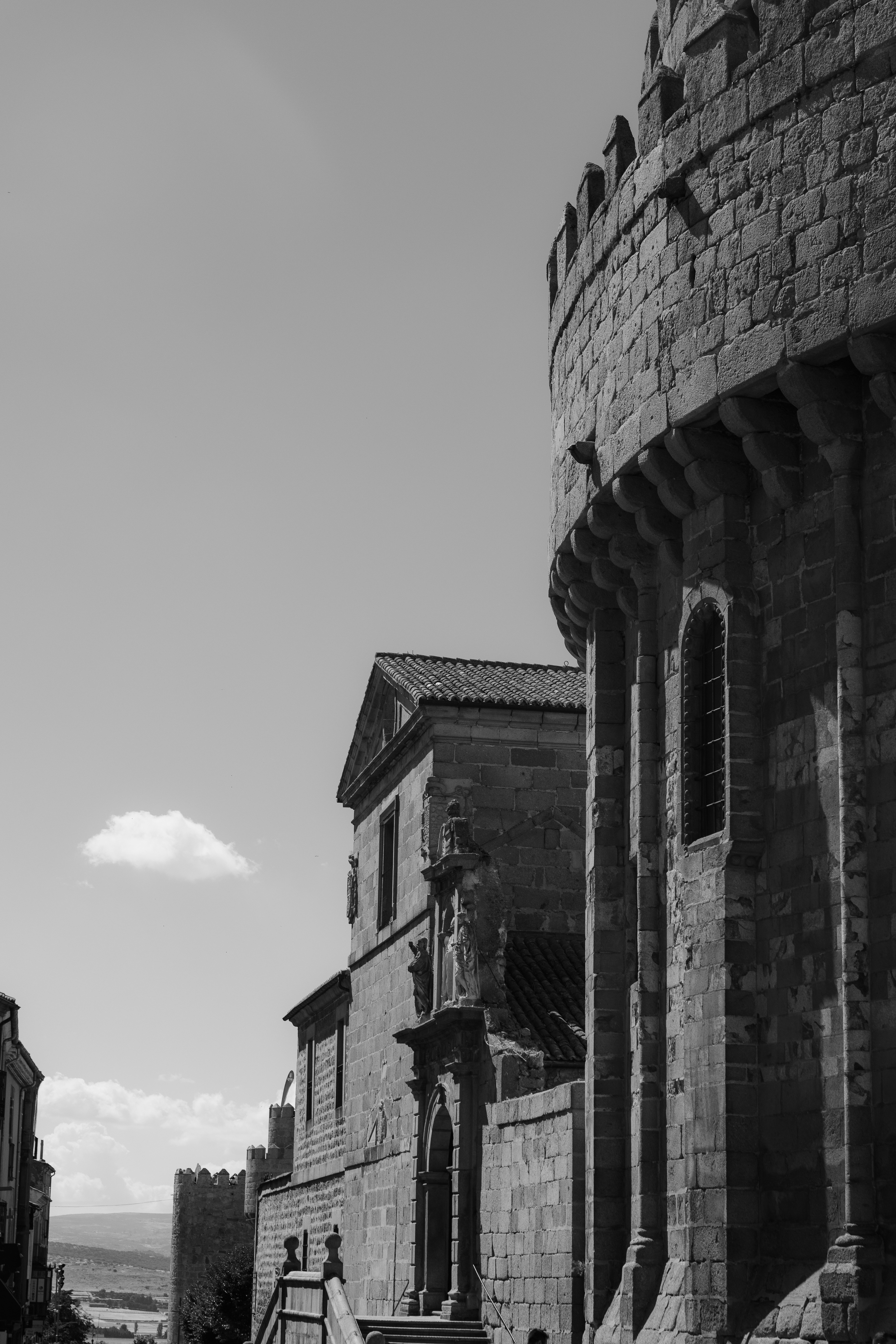 A black and white view of stone medieval fortifications and a church building