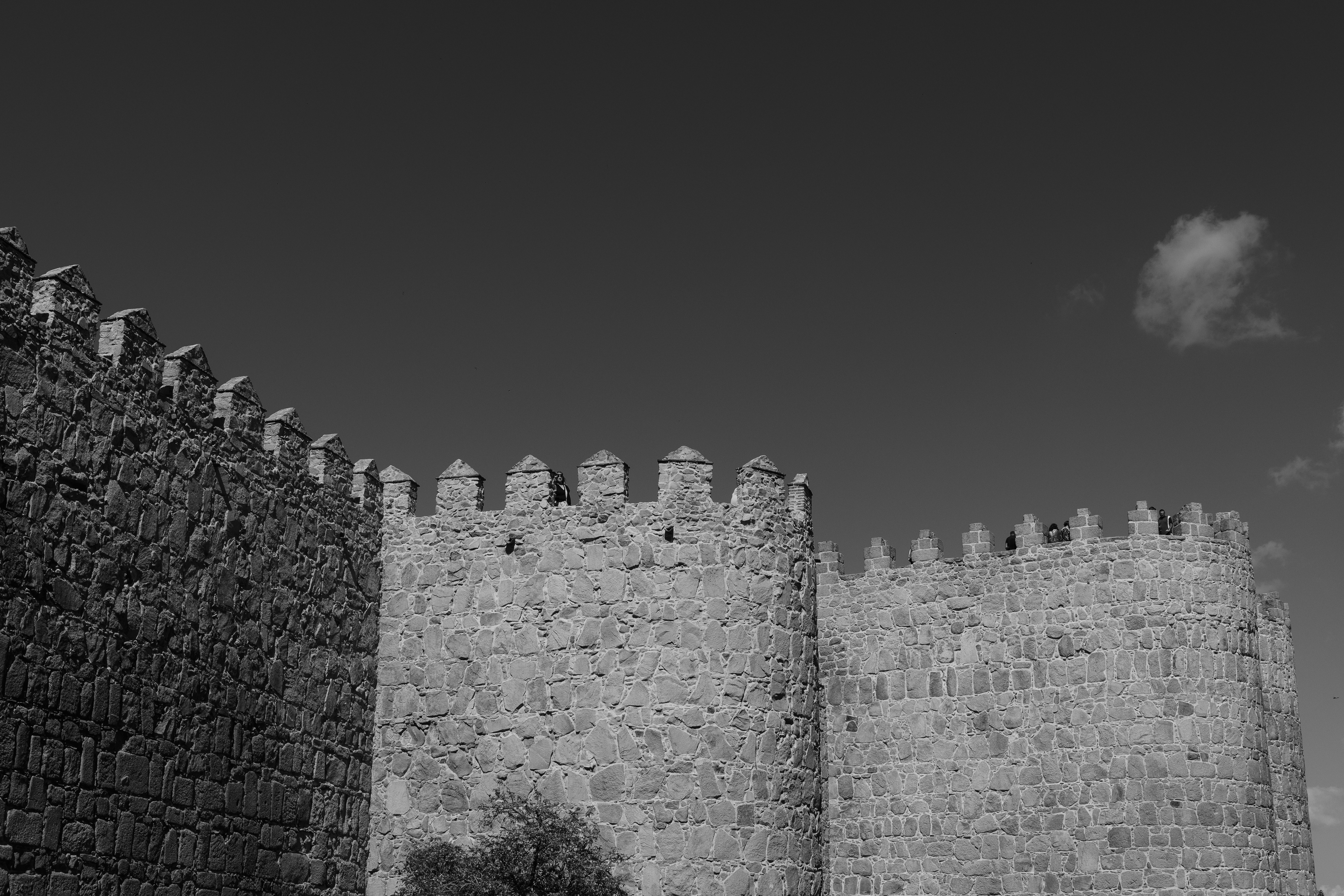 A black and white view of stone fortification walls with crenellated towers