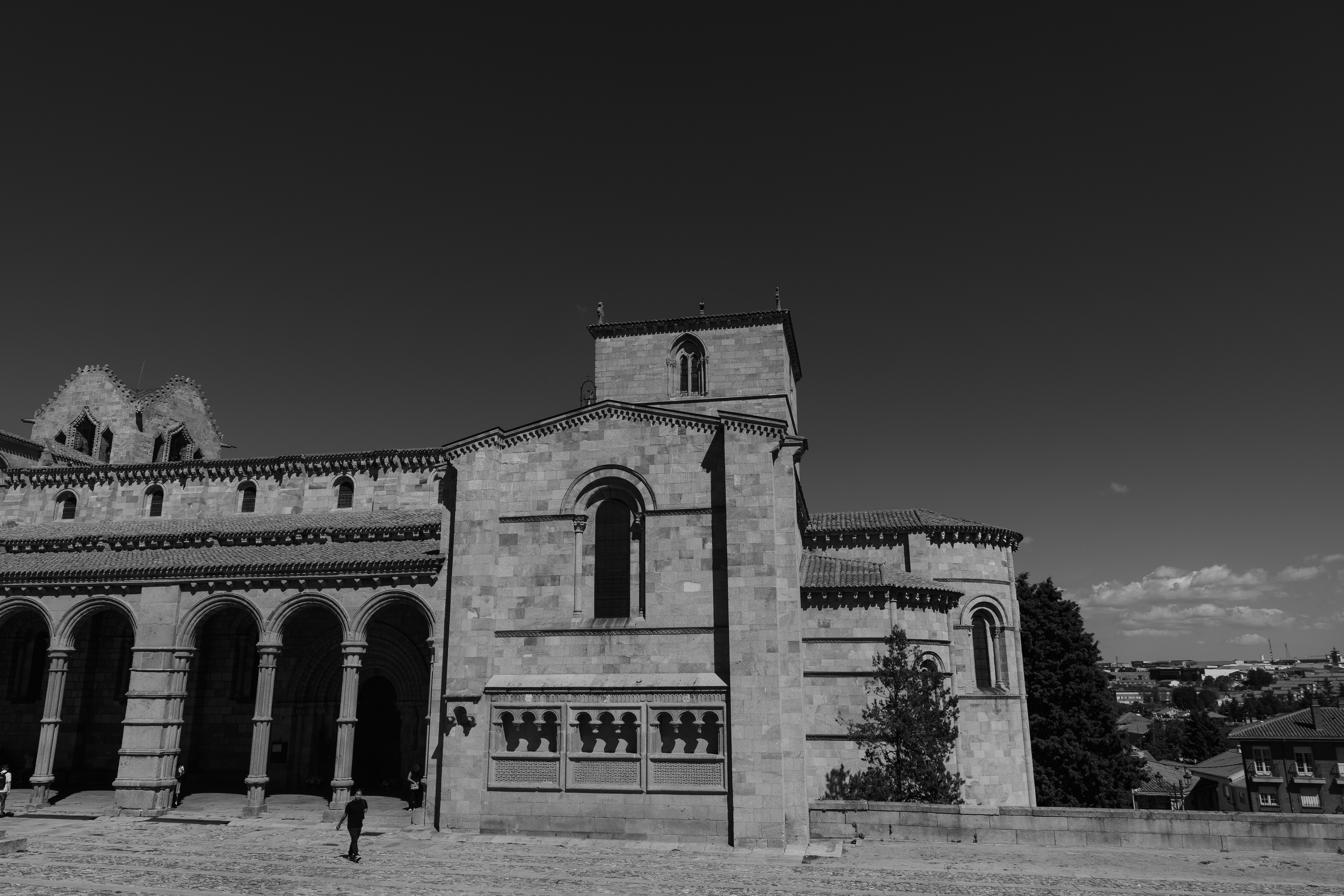 A stone cathedral with arched porticos and a tower under a clear sky