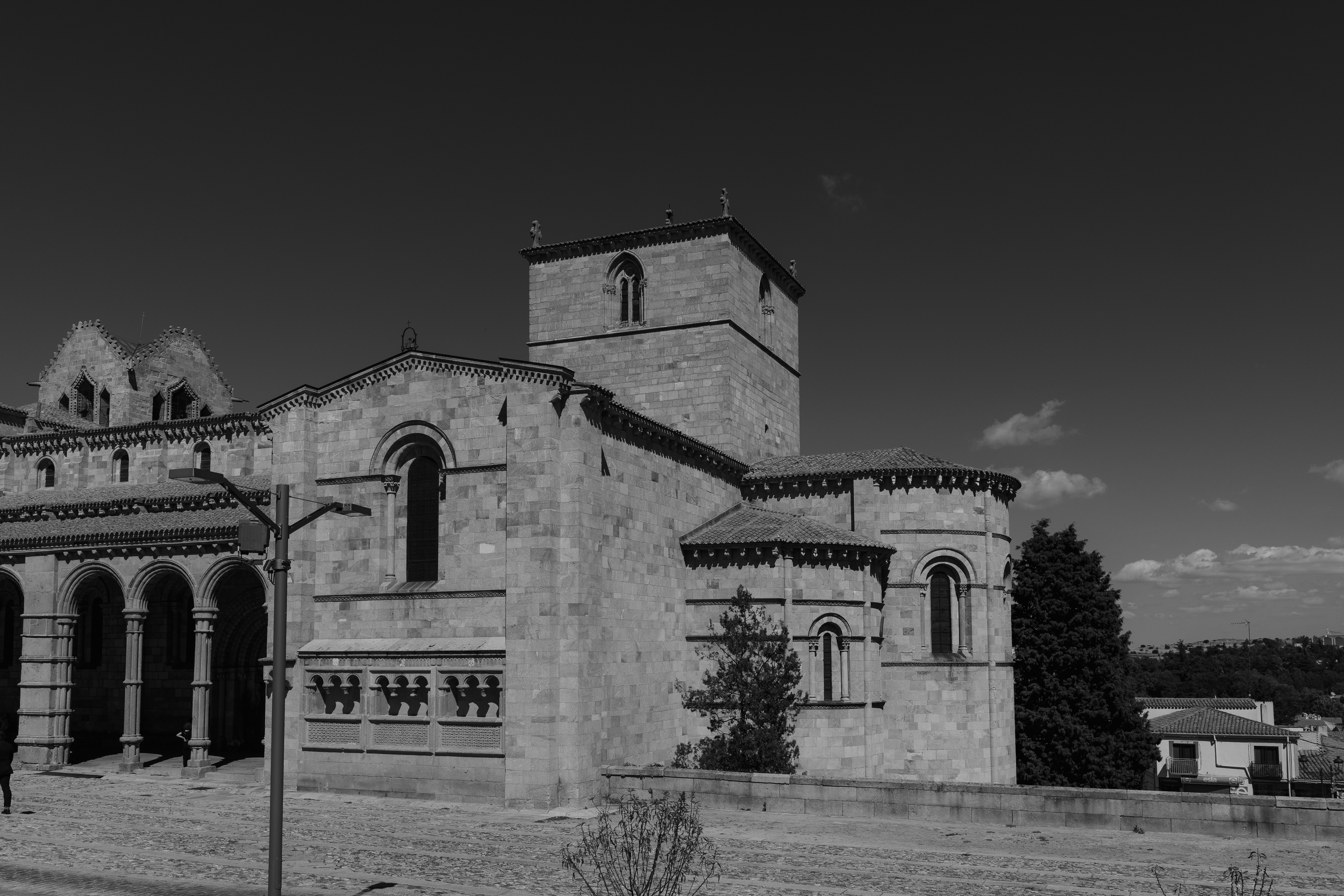 A stone Romanesque cathedral with a square tower under a clear sky