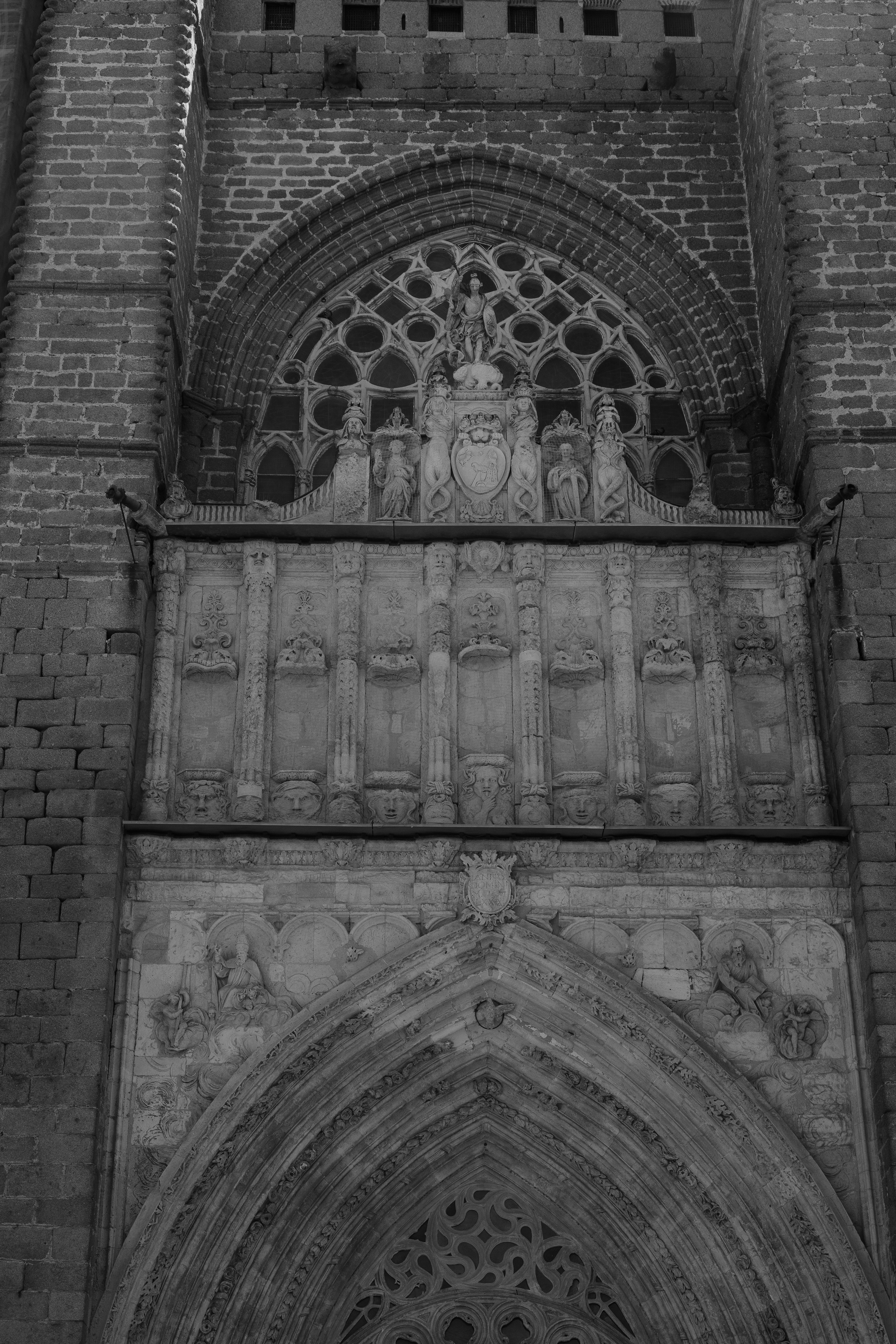 Intricate stone carvings above a gothic arched doorway on a brick cathedral facade