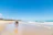 A man and a woman walking along a sandy beach under a clear sky