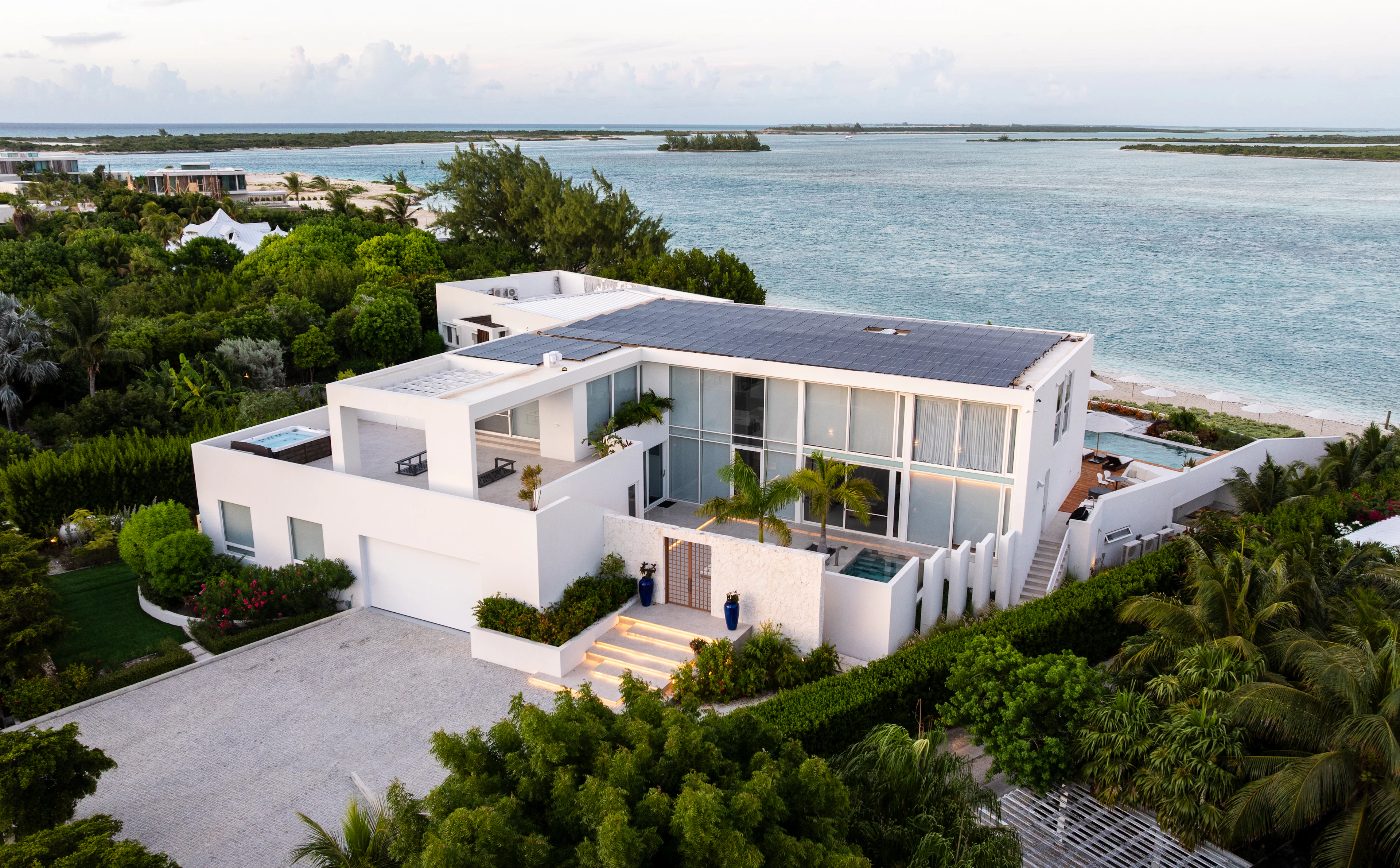 Residencia contemporánea blanca rodeada de vegetación tropical junto al mar