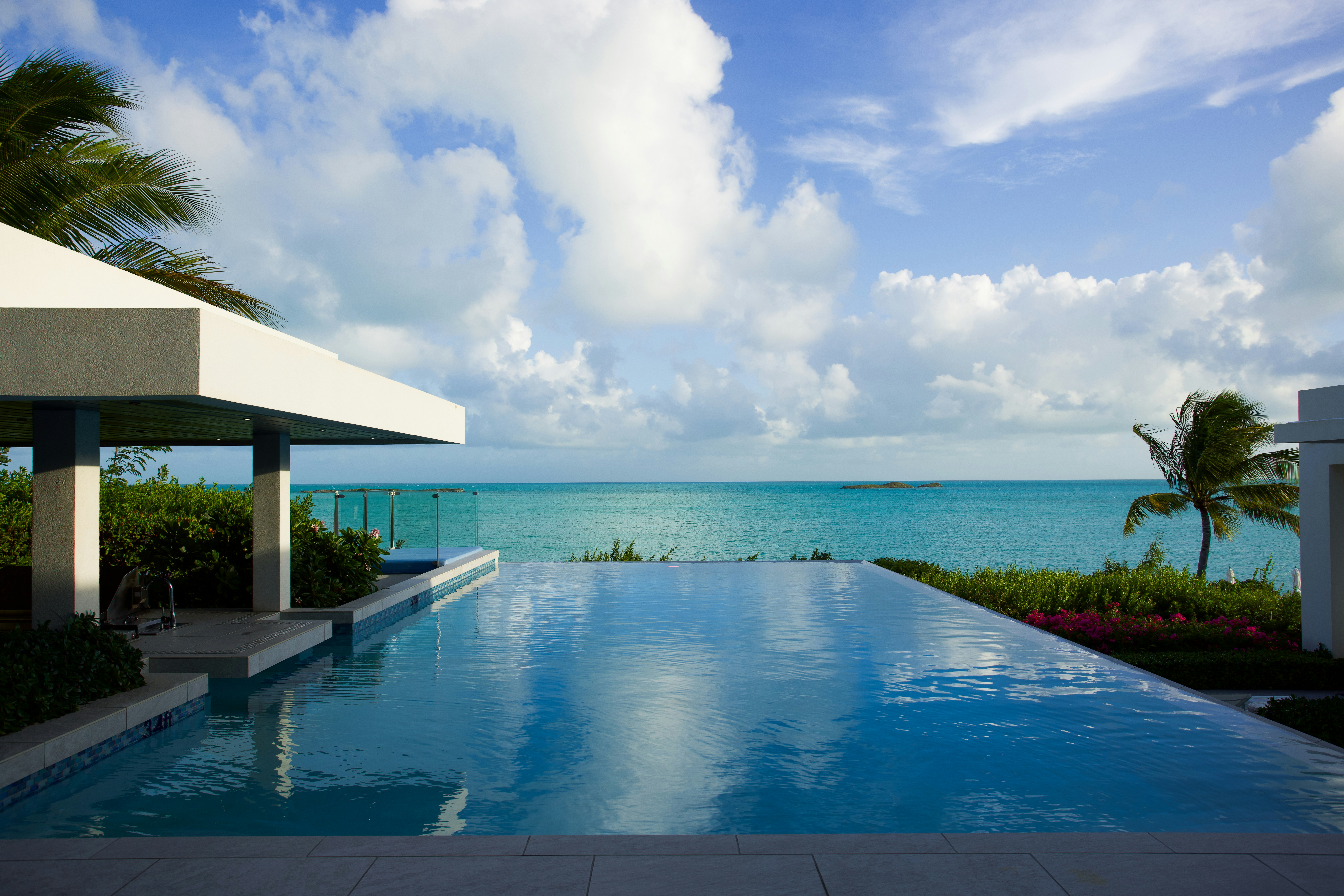 Piscine à débordement face à la mer turquoise sous un ciel bleu